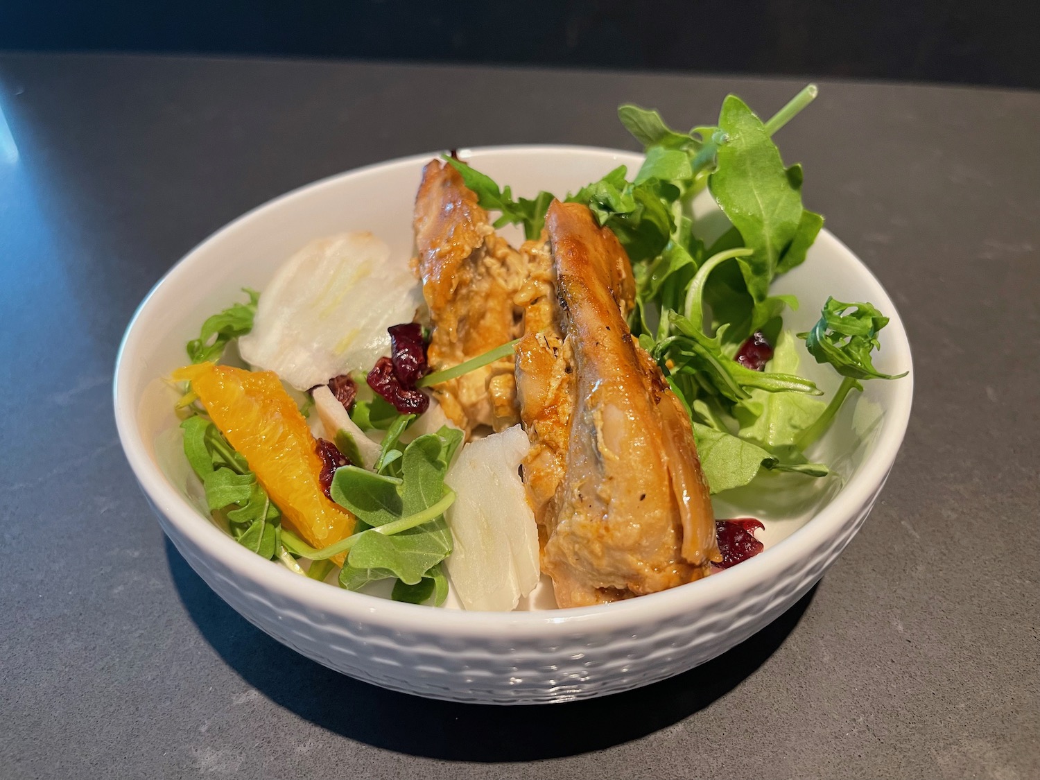 a bowl of salad with meat and oranges