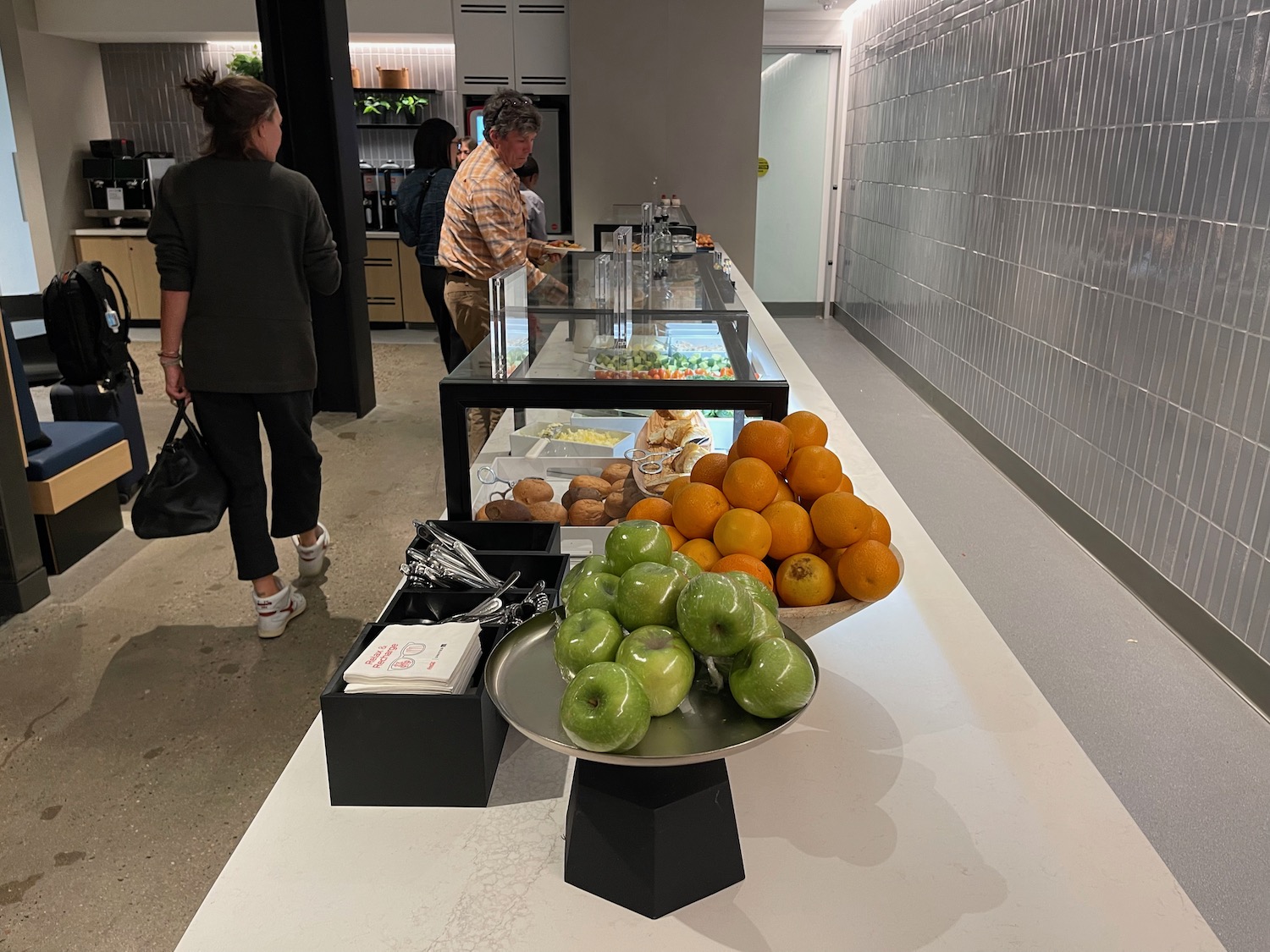 a group of people standing in a room with food on display