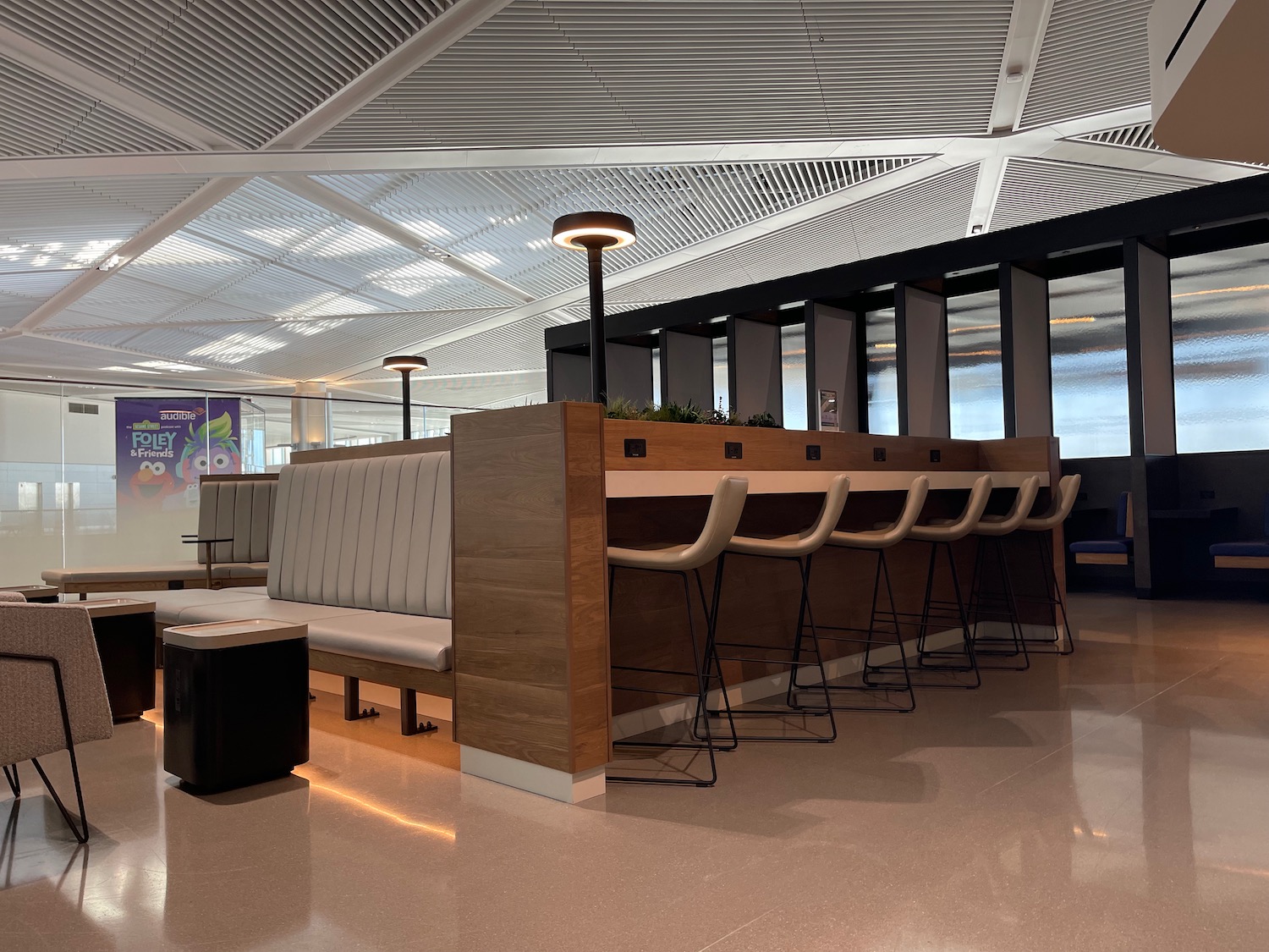 a long table with chairs and a bench in a room with a wall and windows