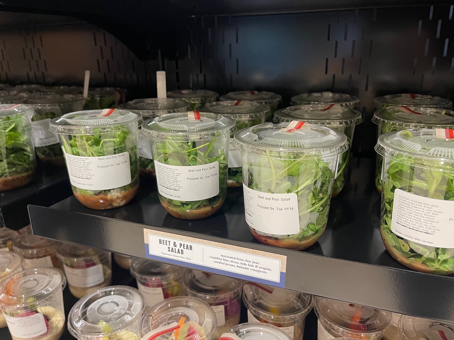 a shelf with plastic containers of salads