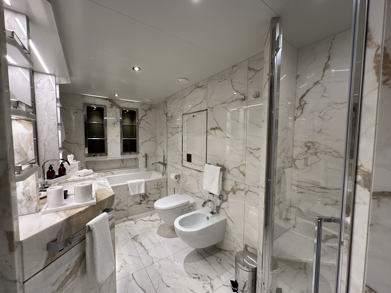 a bathroom with marble walls and a toilet and tub