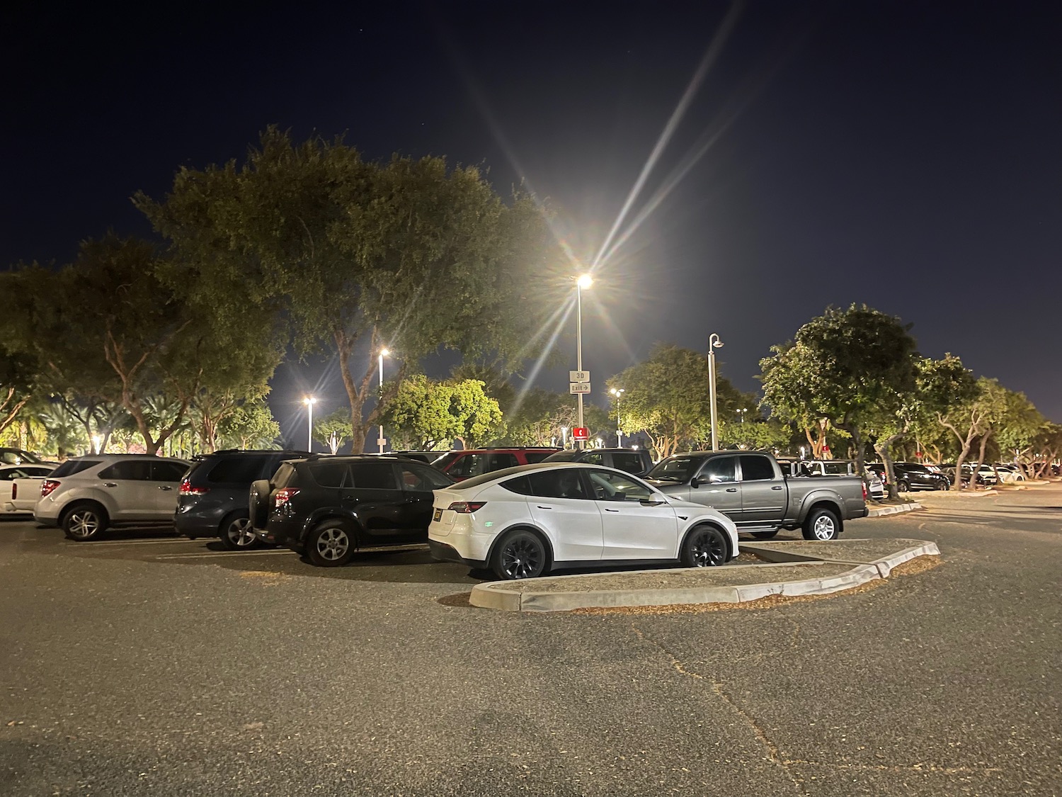 a parking lot with cars and trees at night