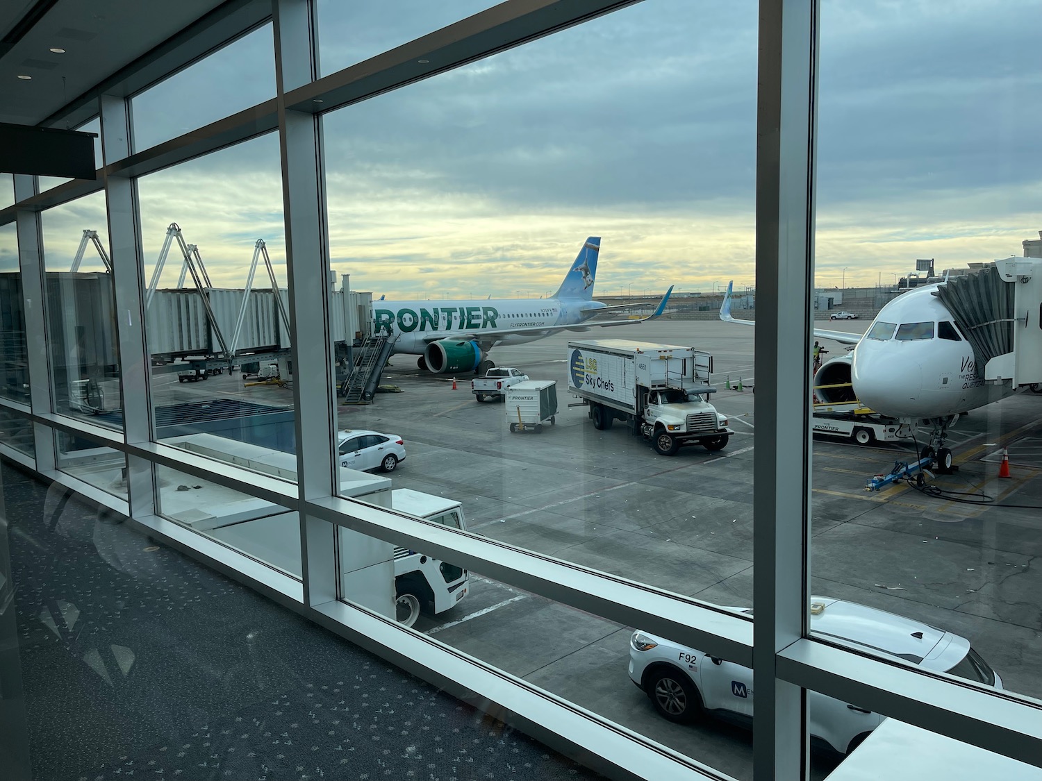 a window view of an airport with airplanes and trucks