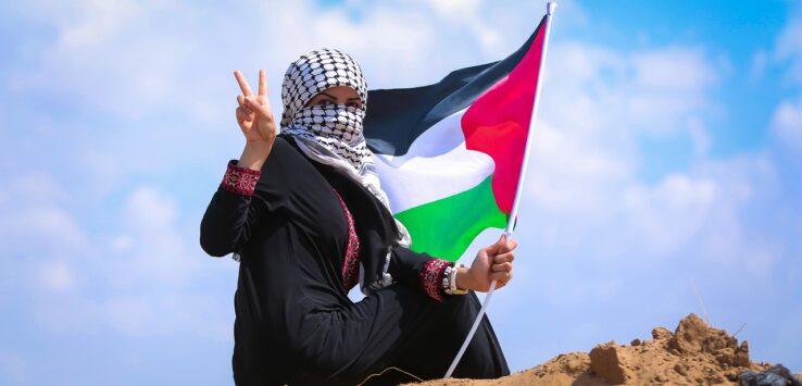 a woman sitting on sand holding a flag