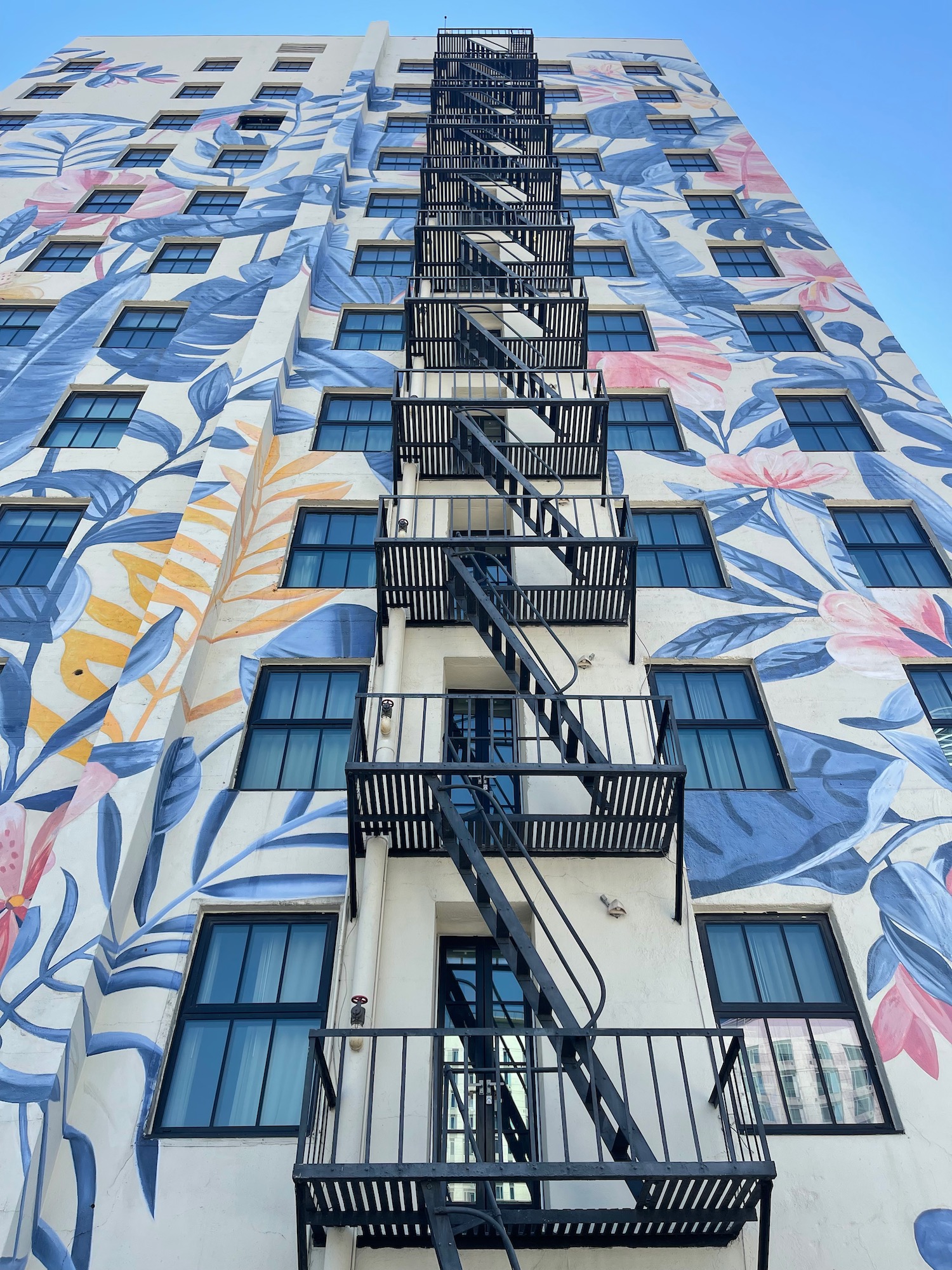 a building with a mural of flowers and fire escape