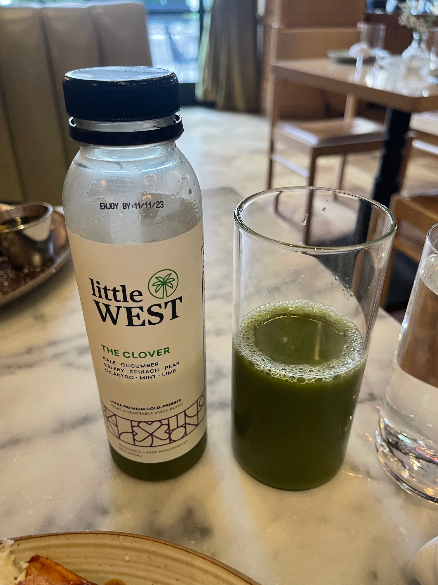 a bottle of juice next to a glass of green liquid