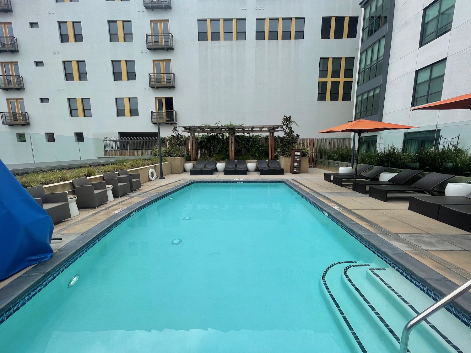 a swimming pool with chairs and umbrellas in front of a building