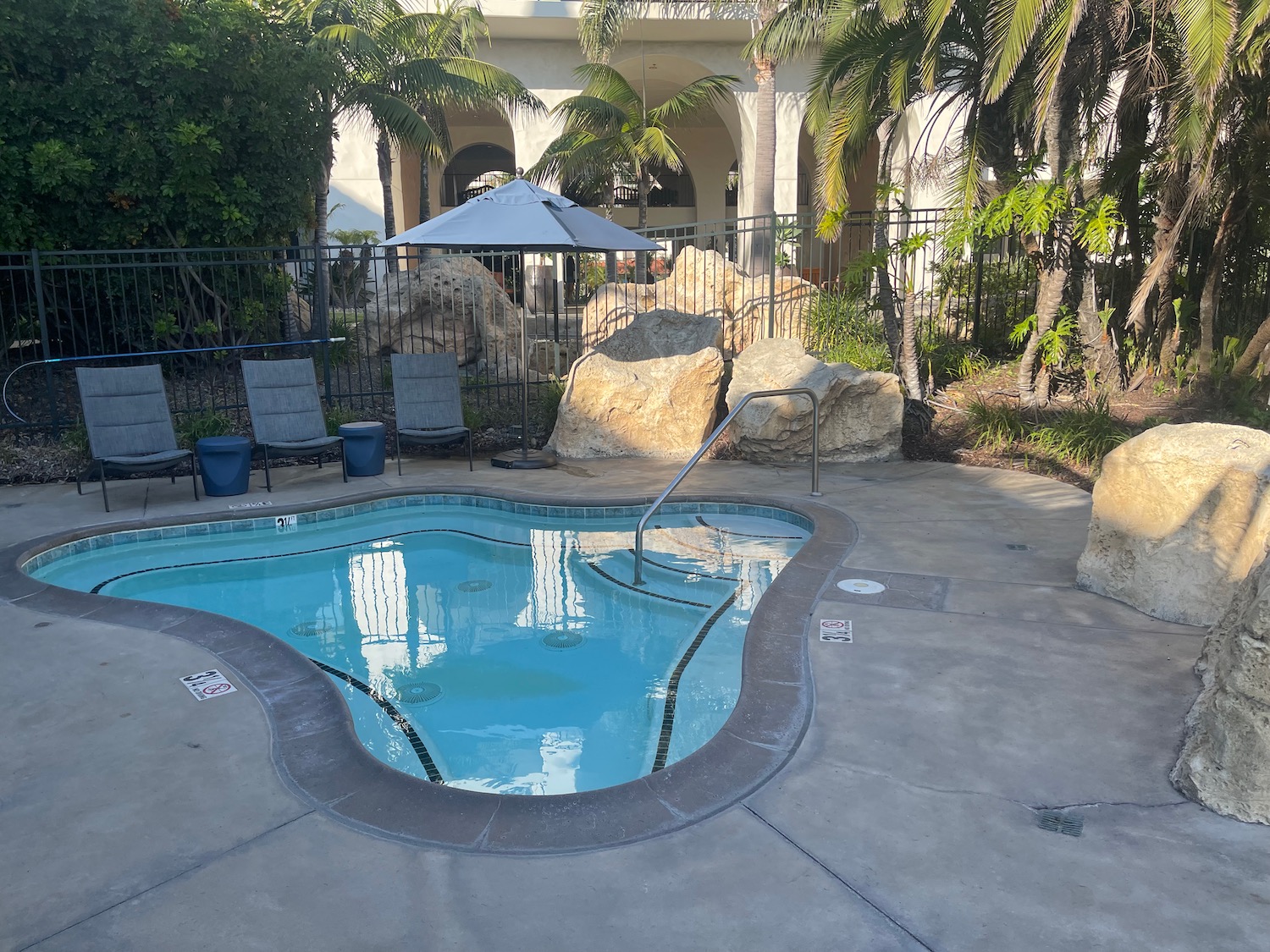 a pool with a metal railing and chairs