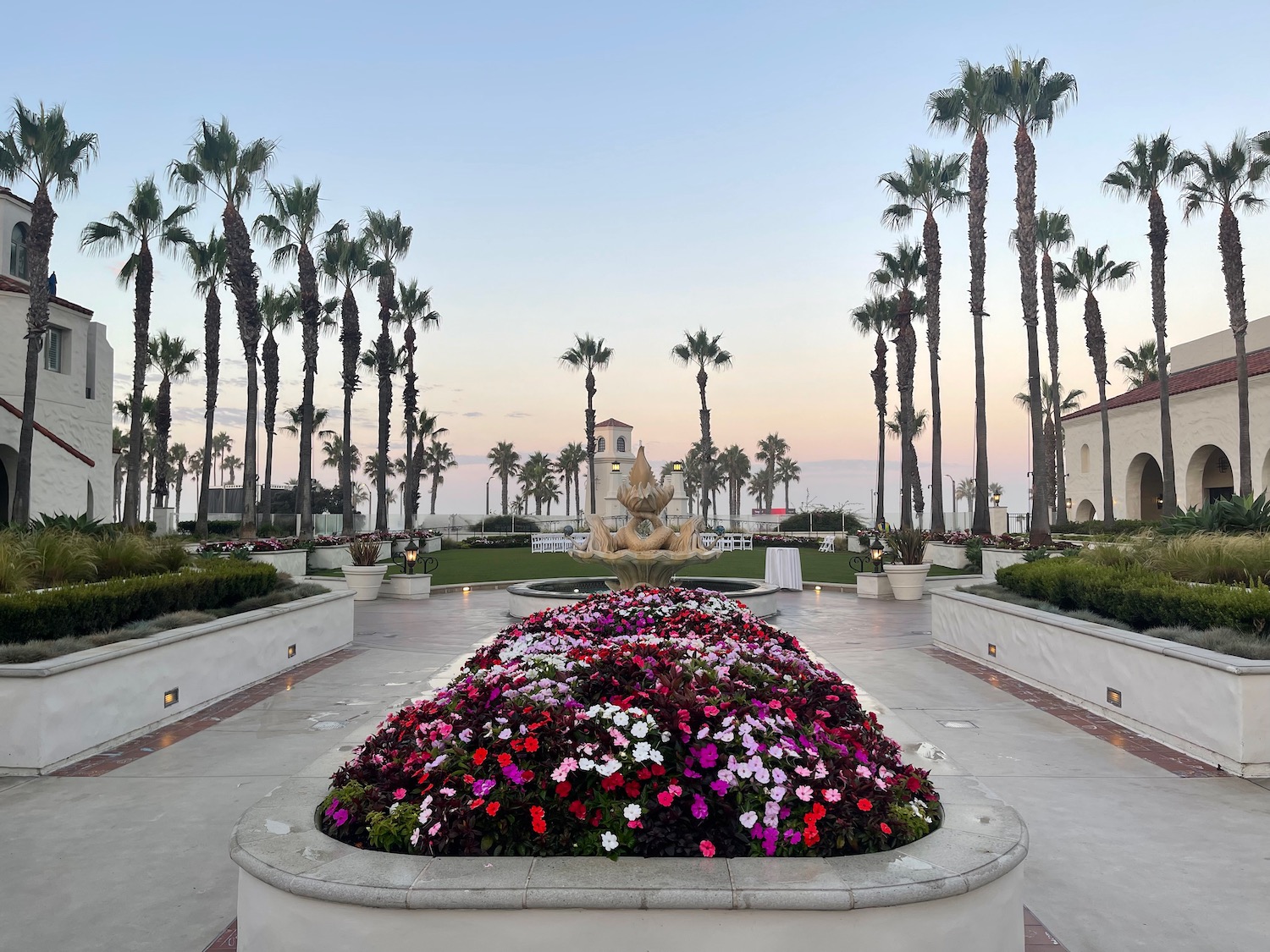 a large courtyard with flowers and palm trees