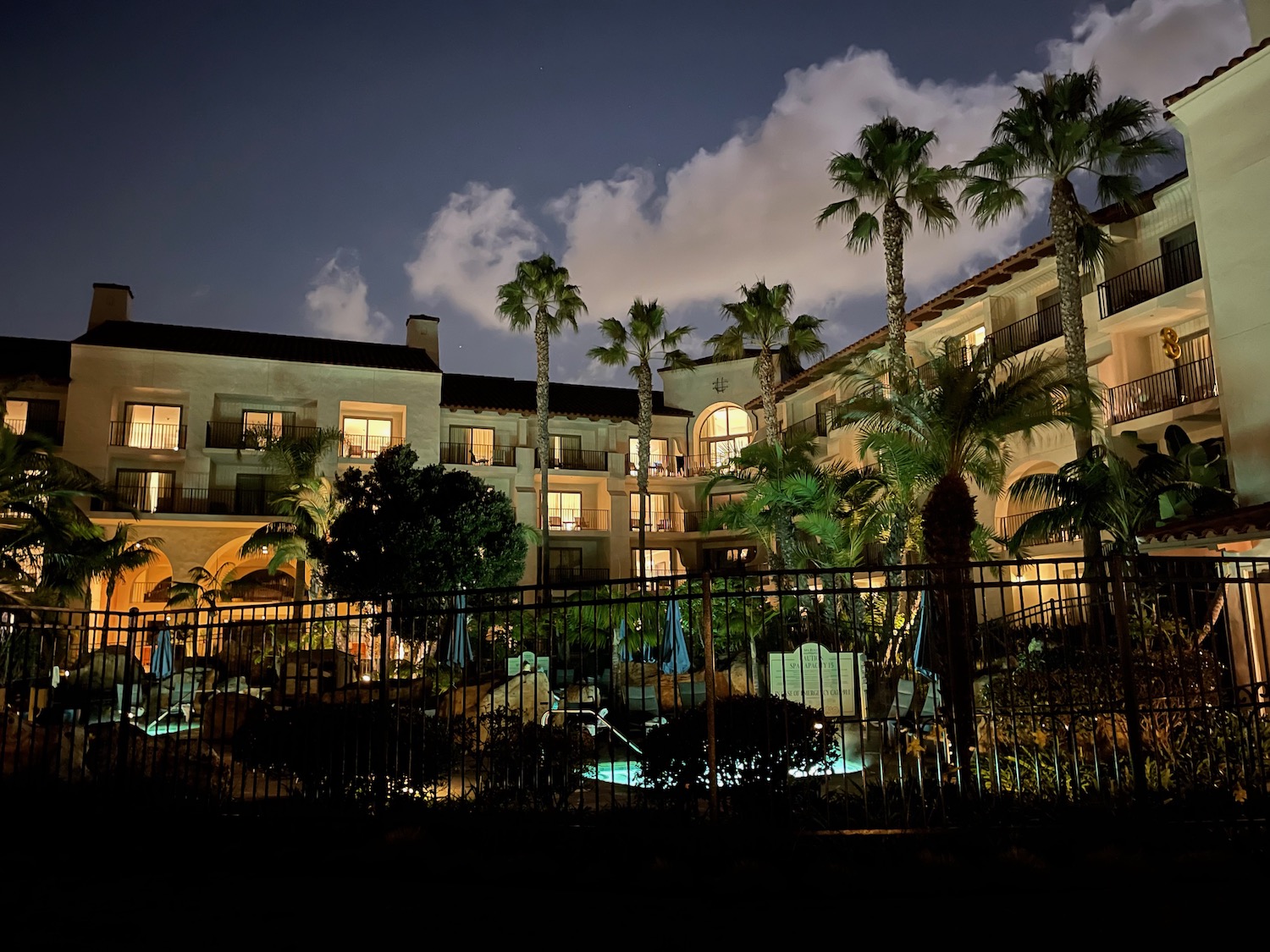 a building with palm trees and a fence