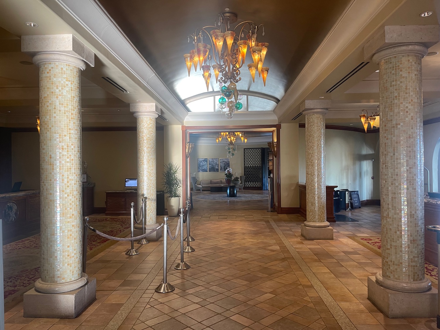 a hallway with columns and chandeliers