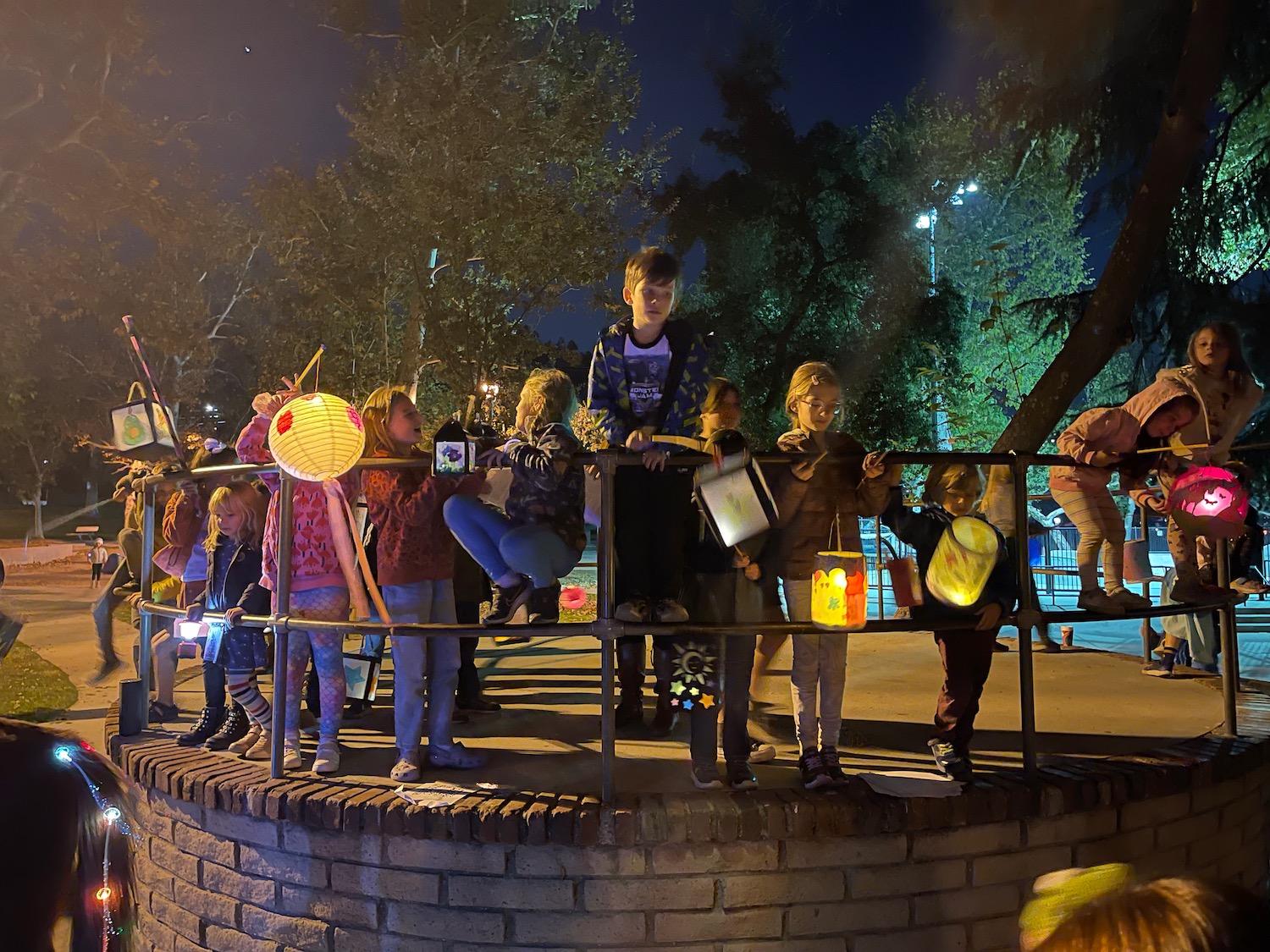 a group of children standing on a brick wall with lanterns