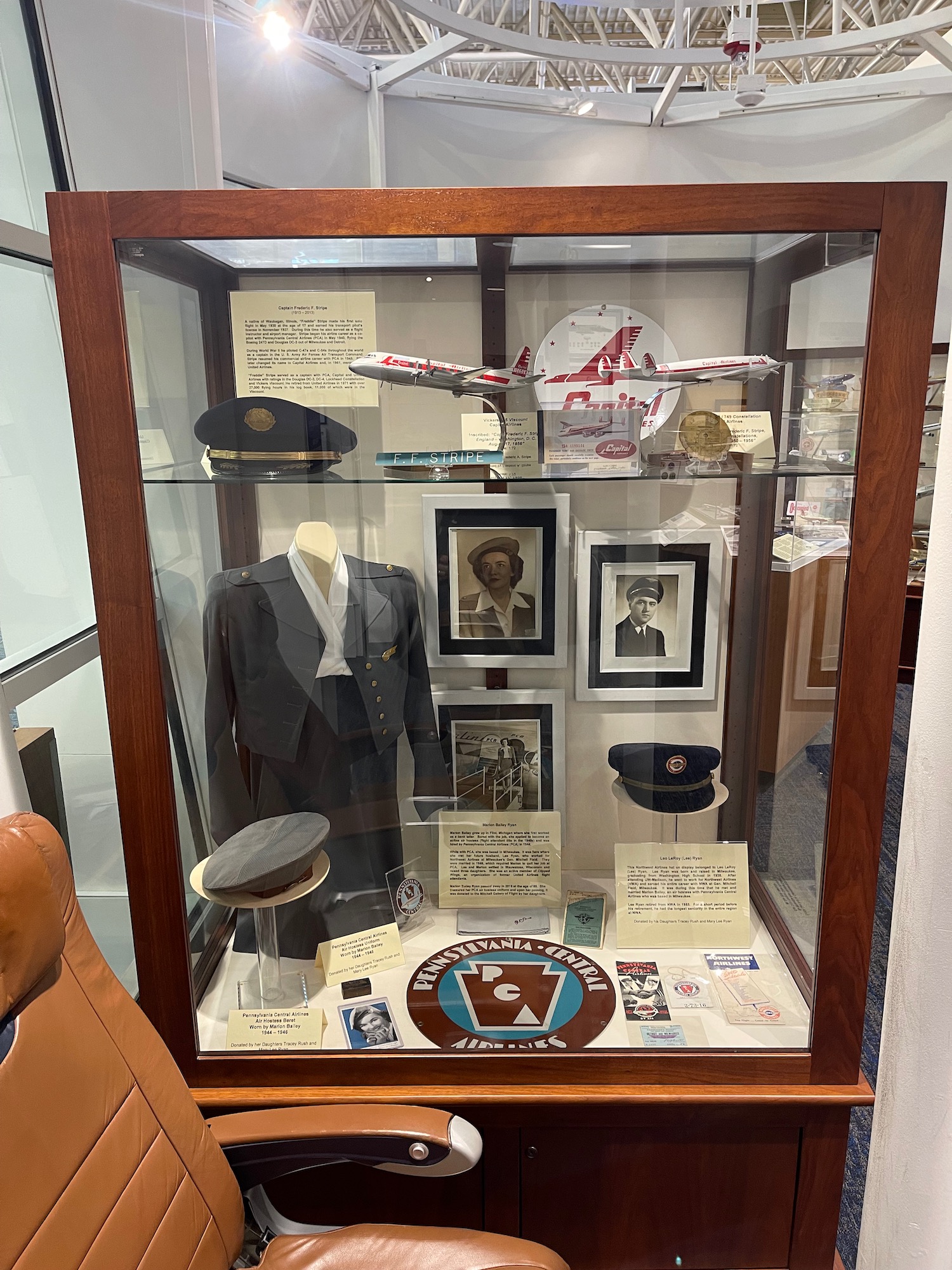 a display case with a plane and a suit and hat