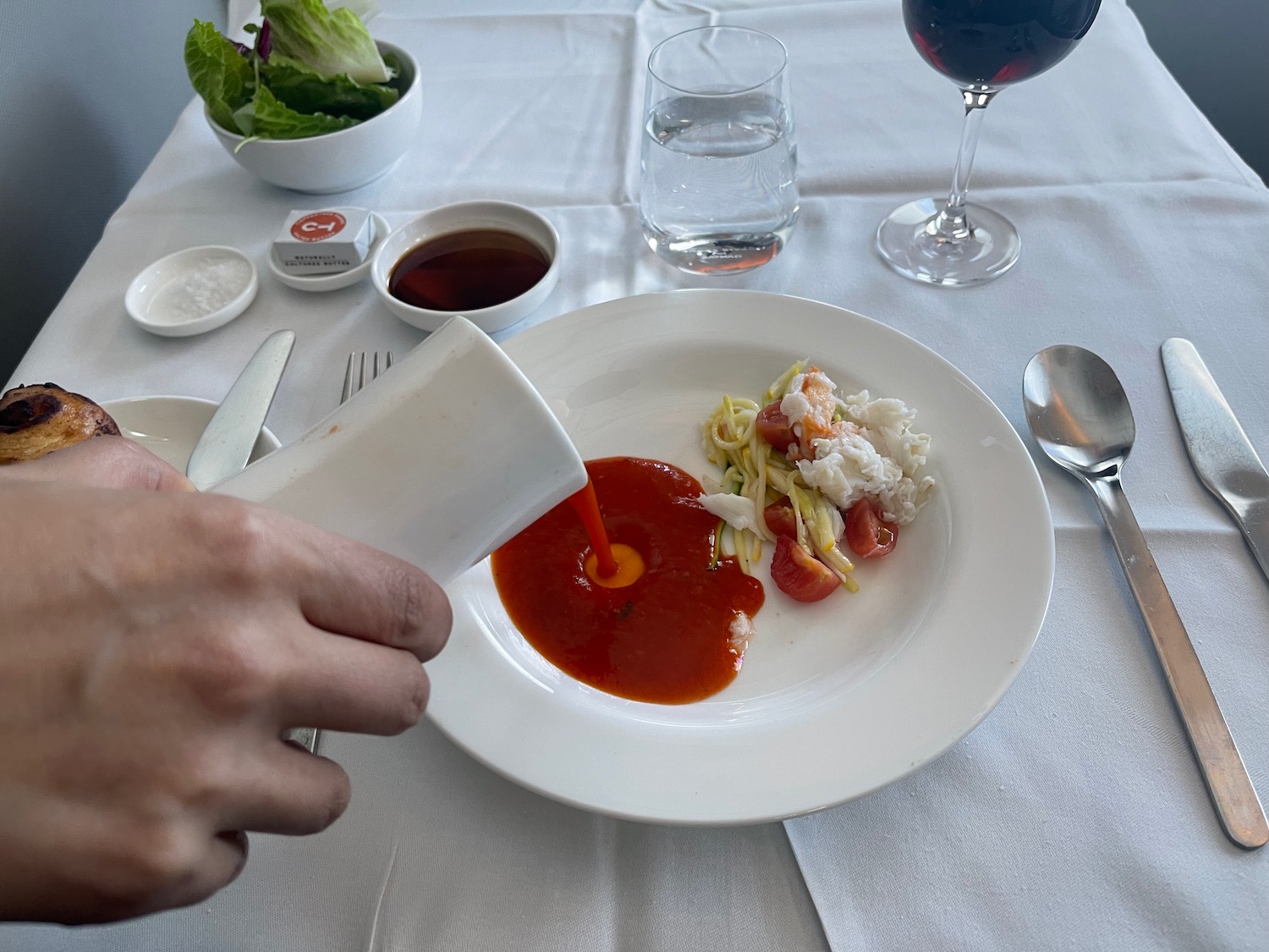 a person pouring sauce into a plate of food
