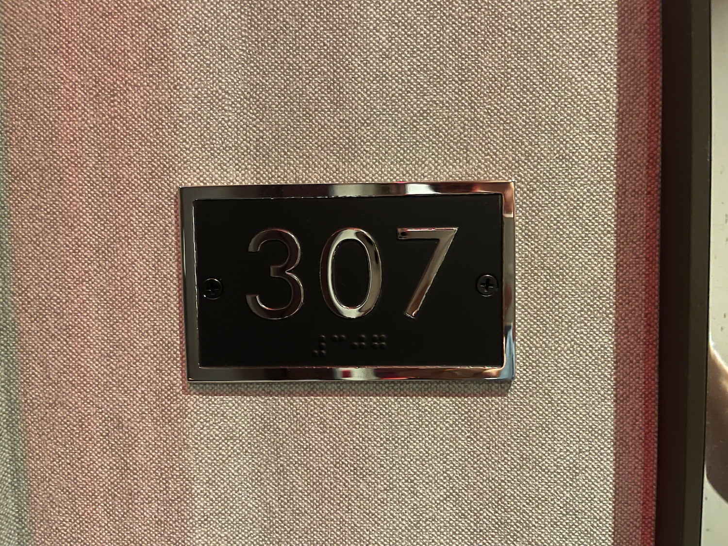 a black rectangular sign with silver numbers on a tan and white fabric