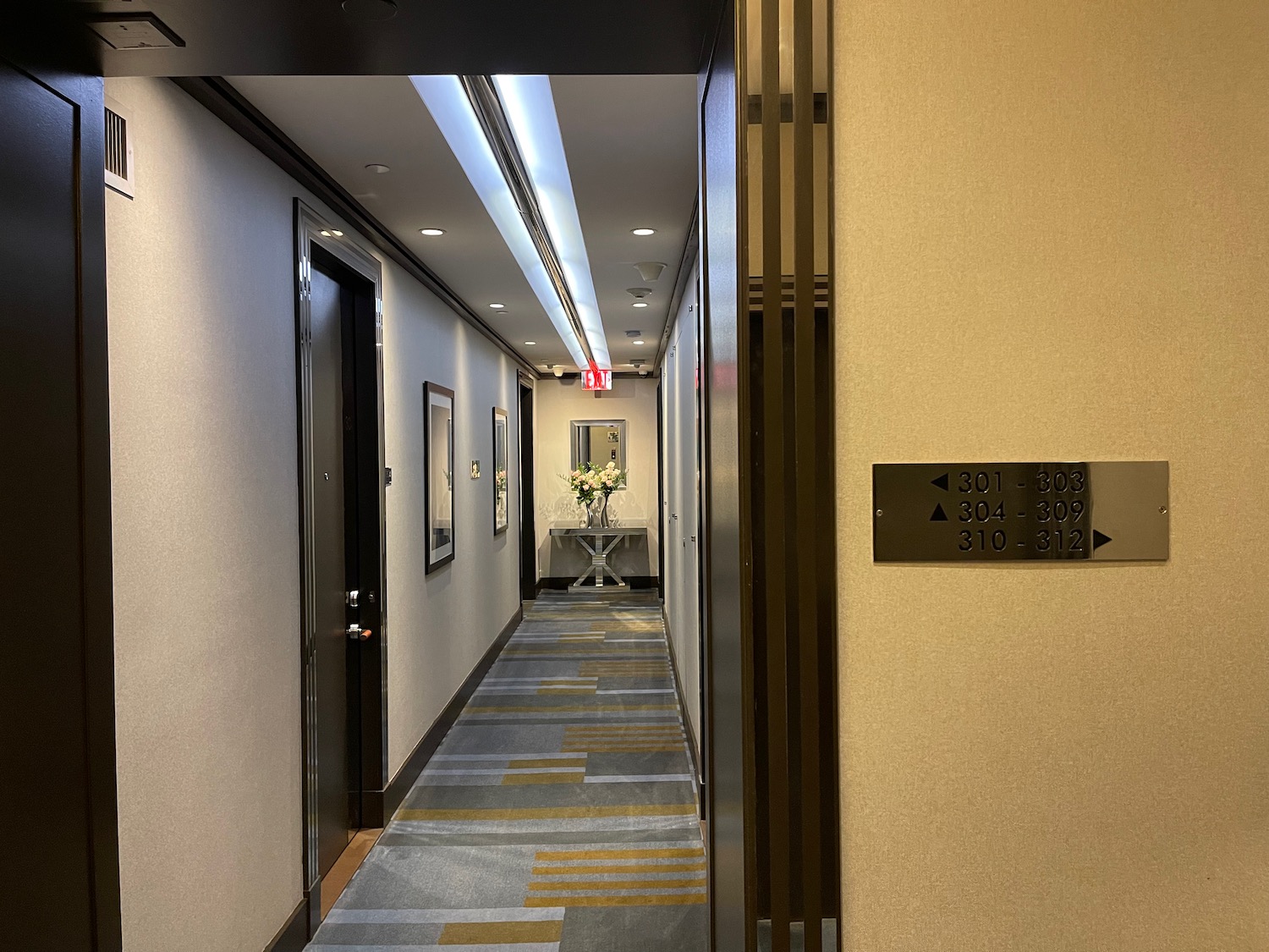 a hallway with a door and a vase of flowers