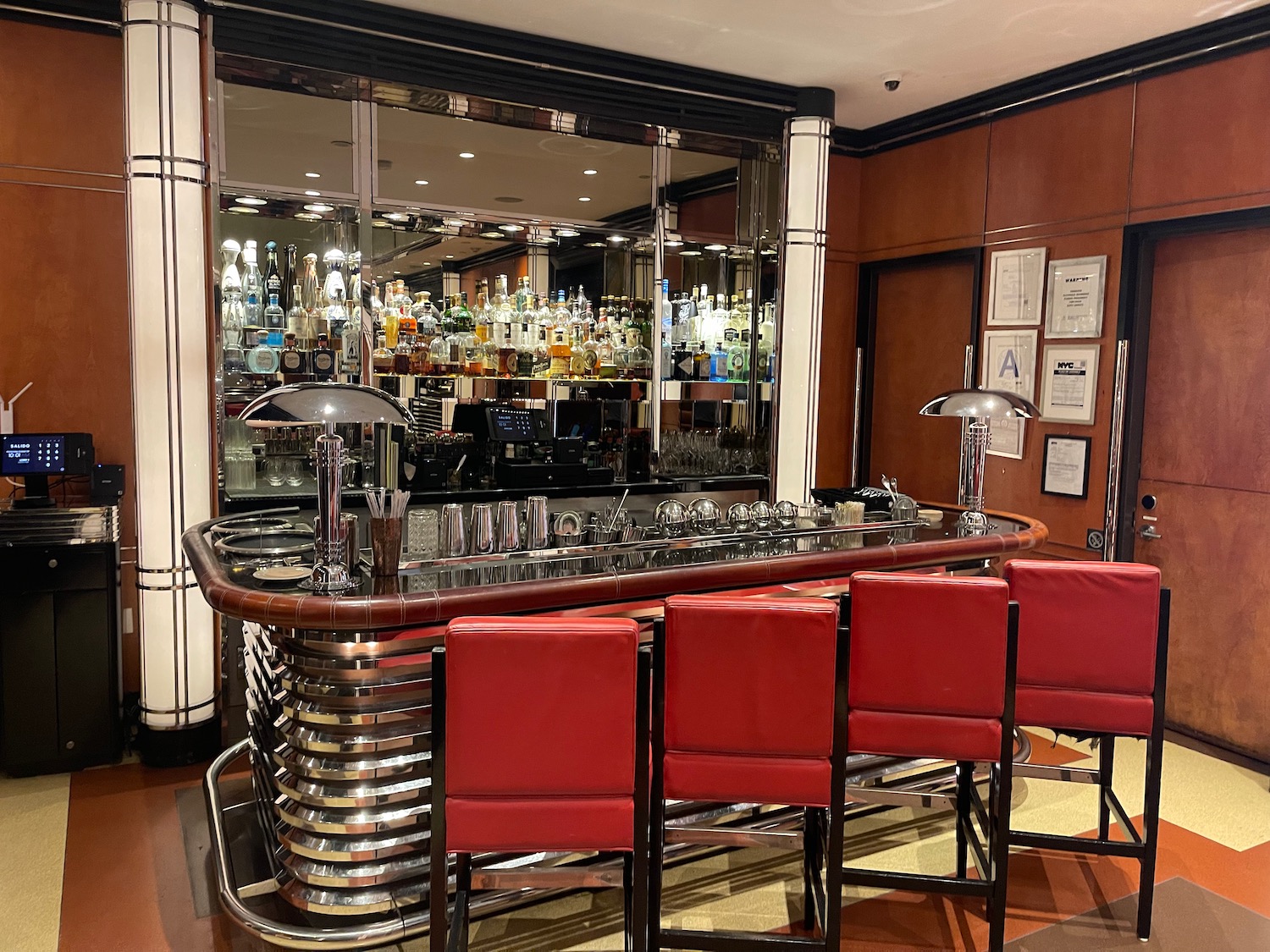 a bar with red chairs and a large mirror