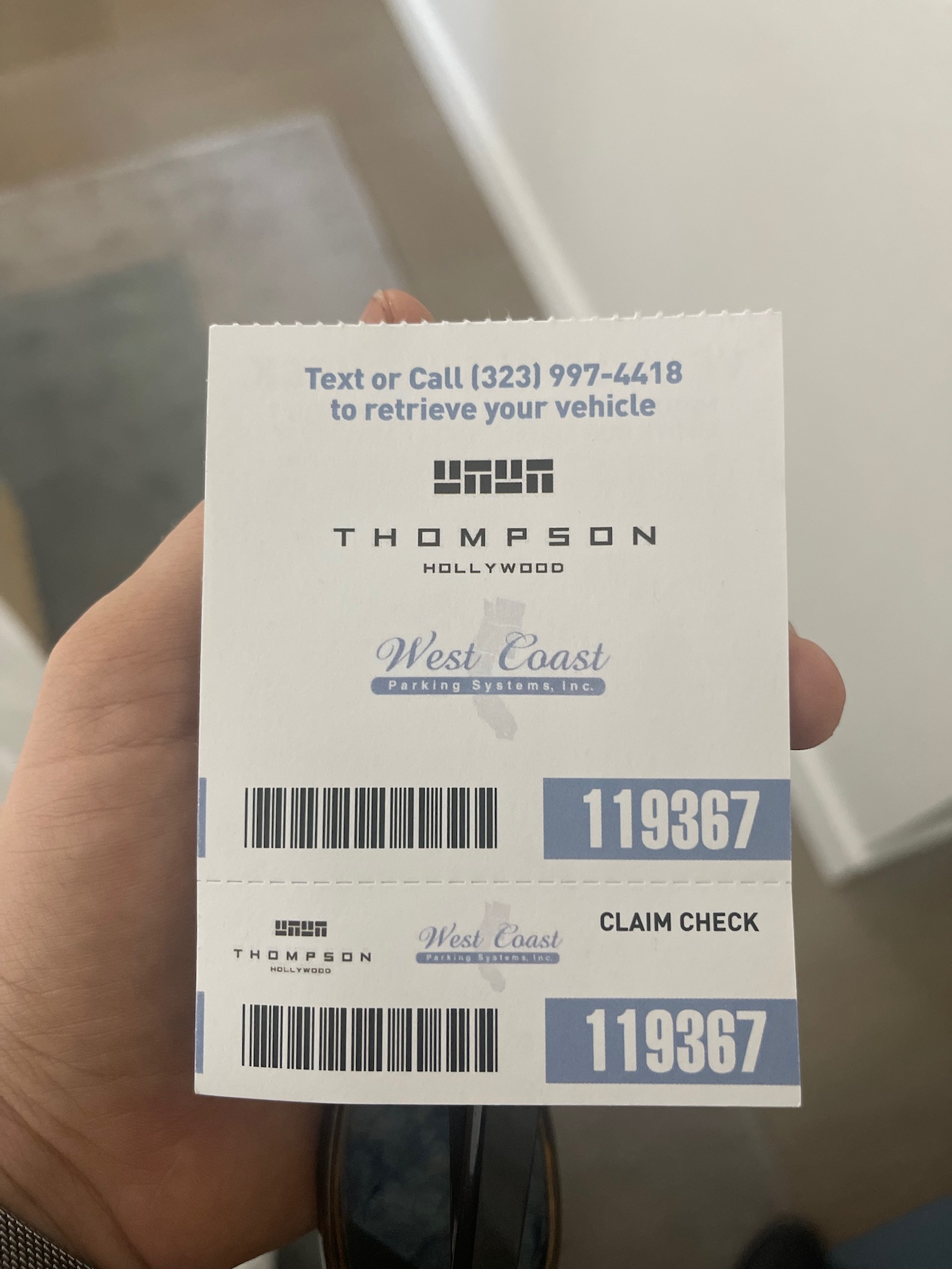 a hand holding a piece of paper with a barcode and numbers