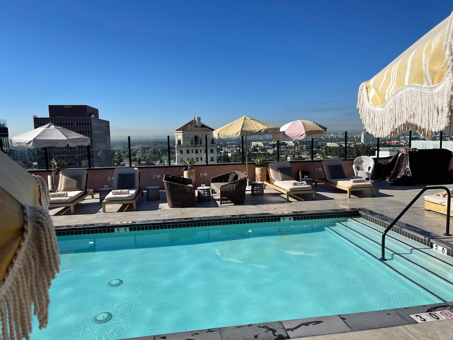 a pool with umbrellas and chairs on a rooftop