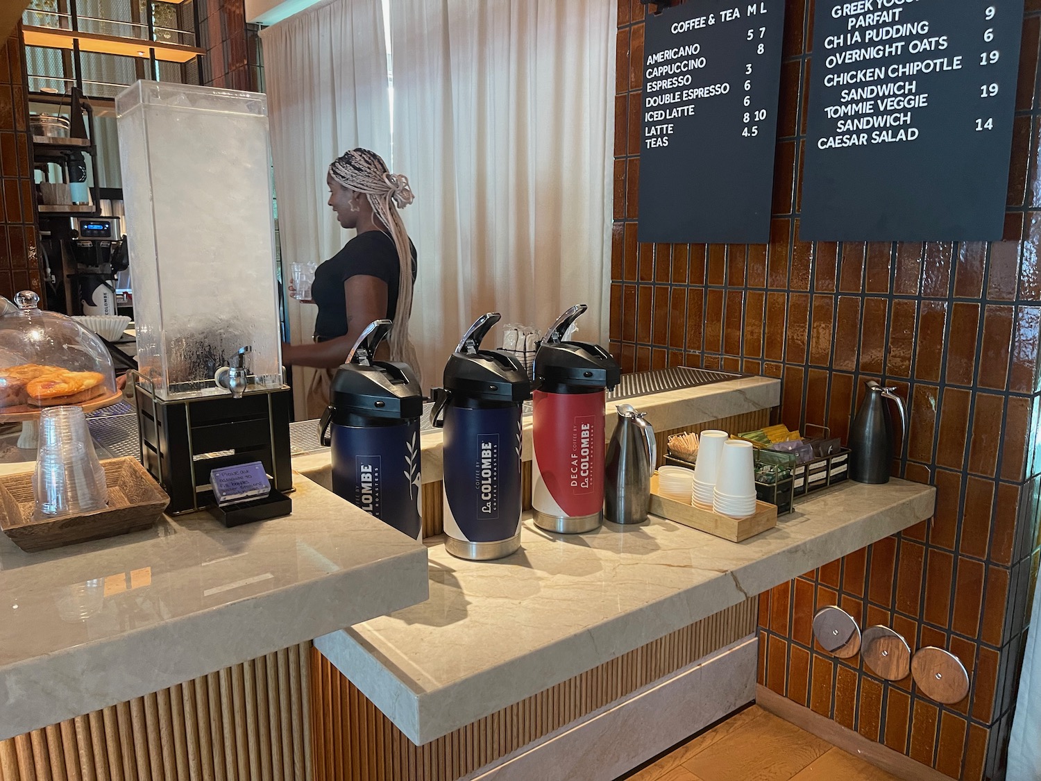 a woman standing behind a counter with several coffee containers