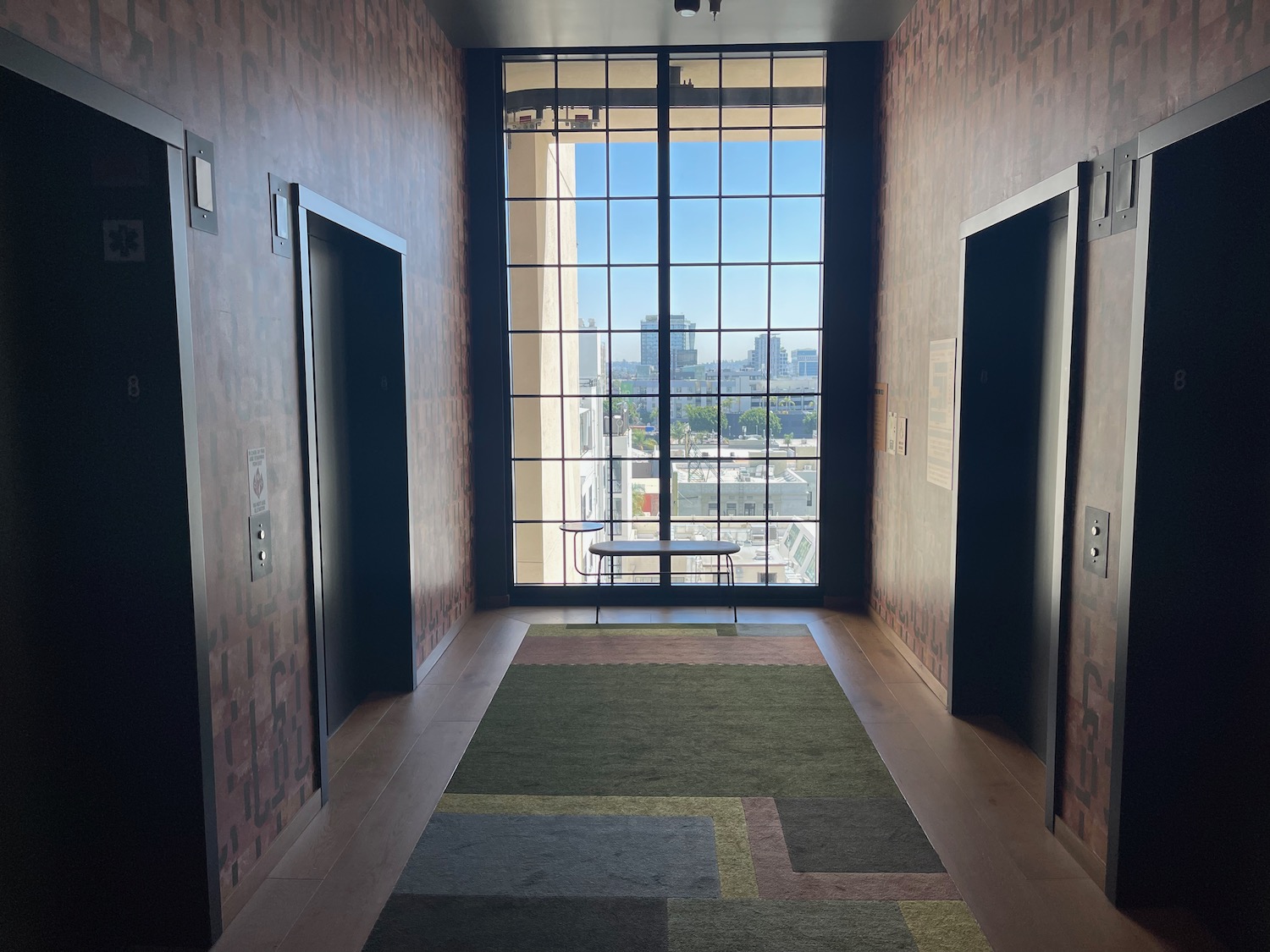 a hallway with two elevators and a bench