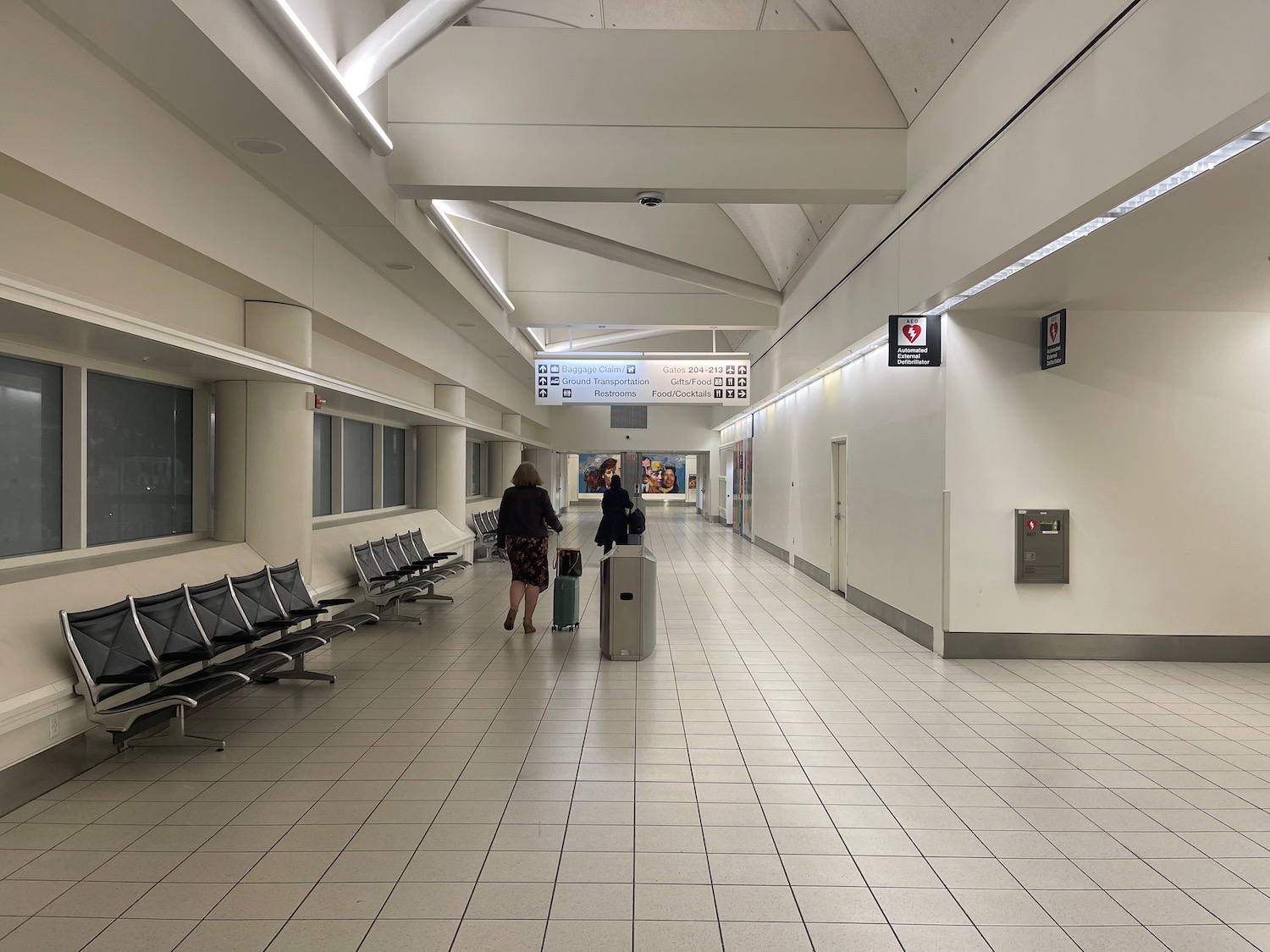people in a white hallway with benches and people walking