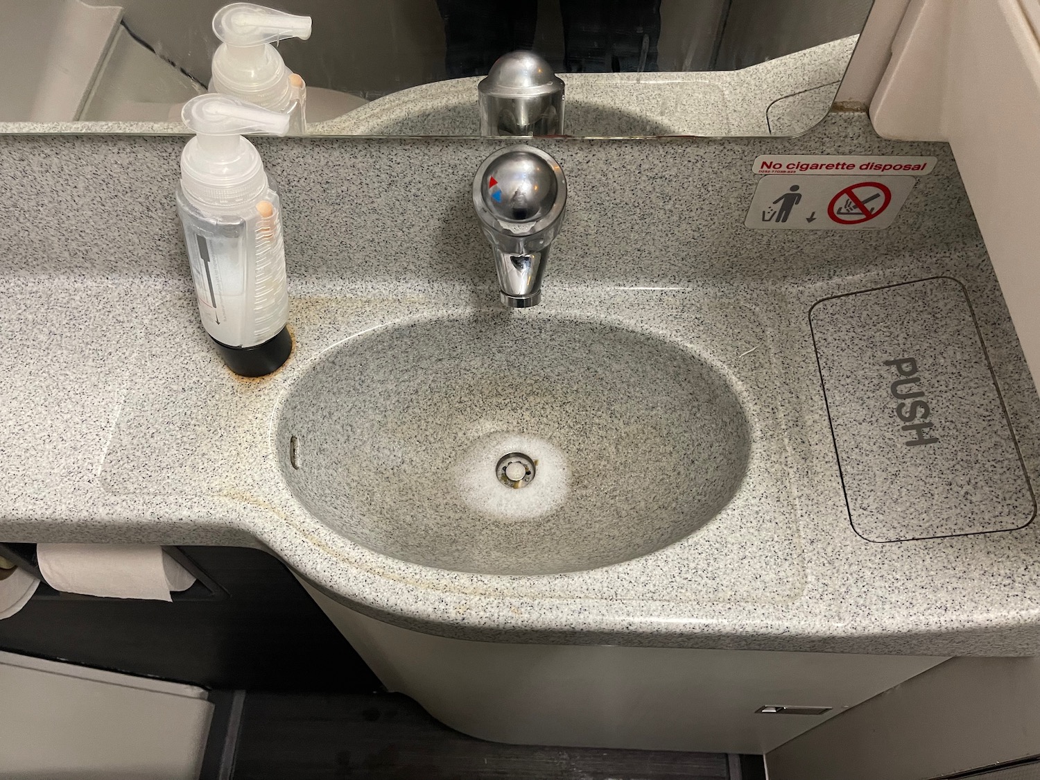 a sink with soap dispenser and bottle of liquid