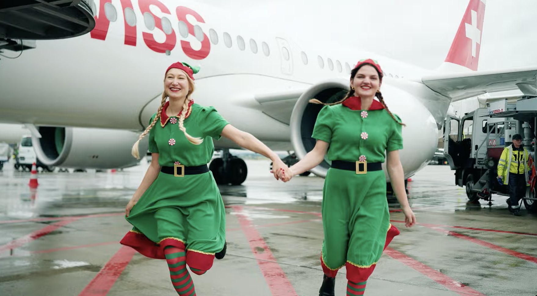 two women in elf clothing holding hands and walking by an airplane
