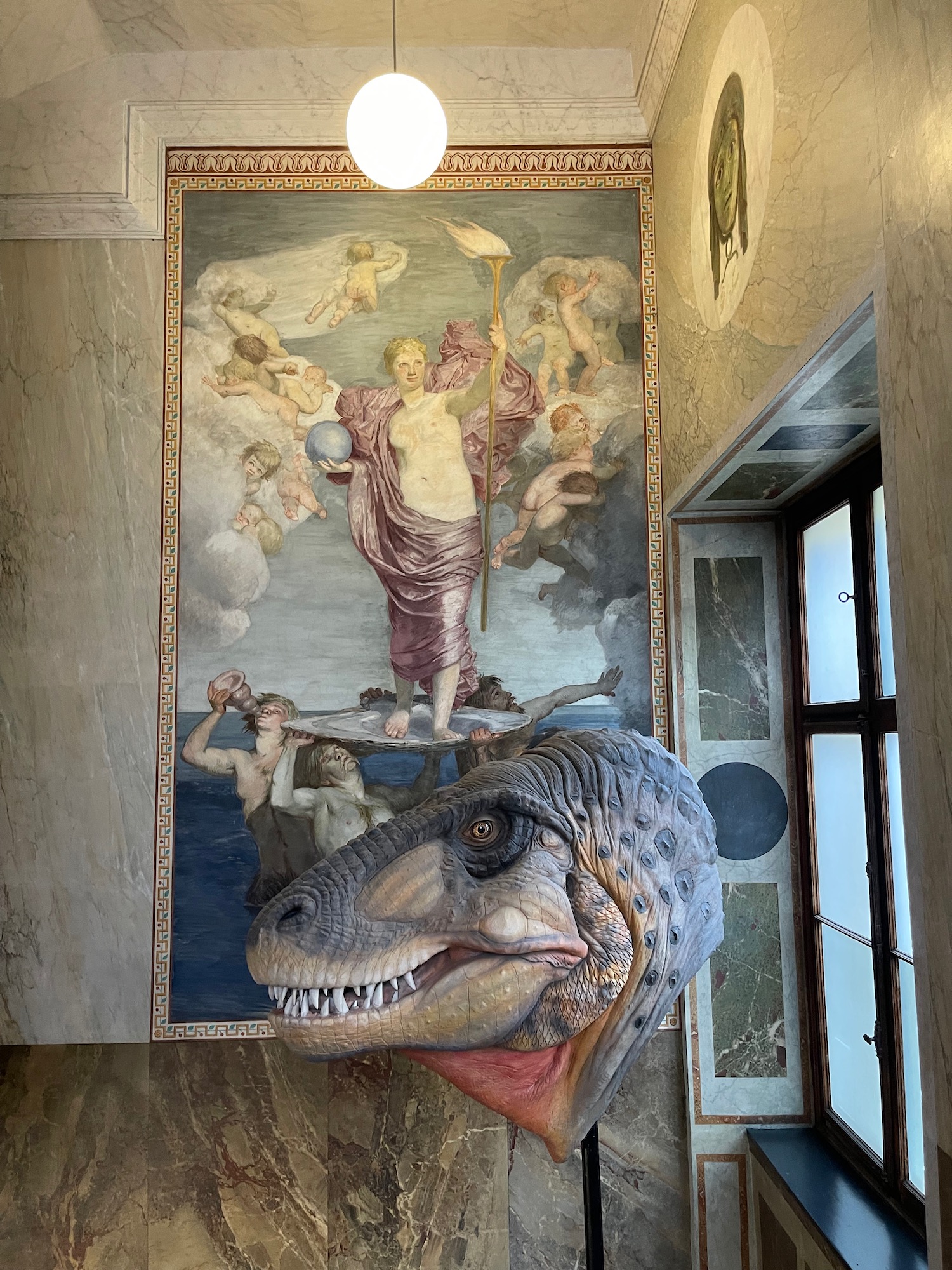 a dinosaur head in a room with a painting on the wall