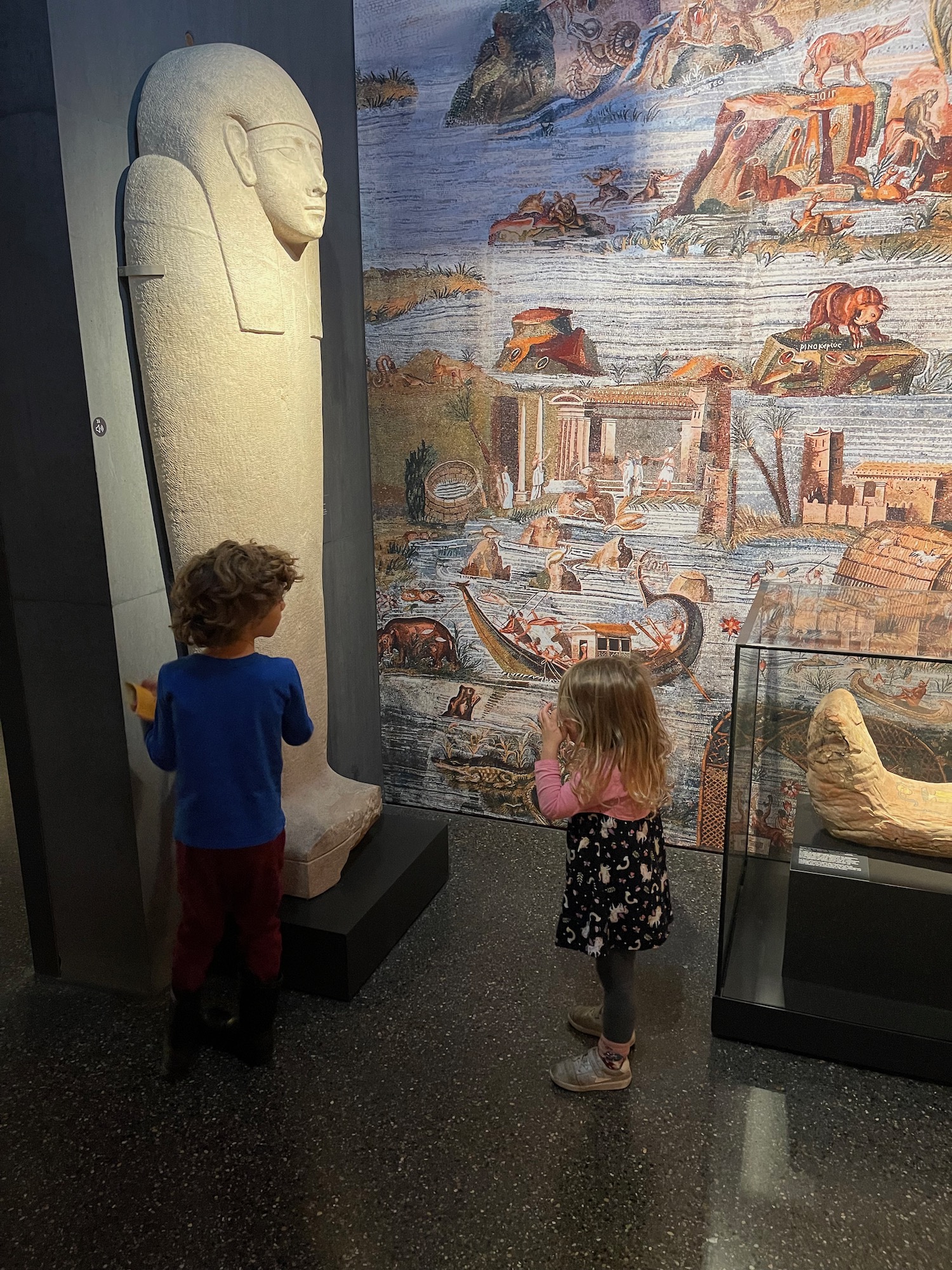 a boy and girl looking at a statue