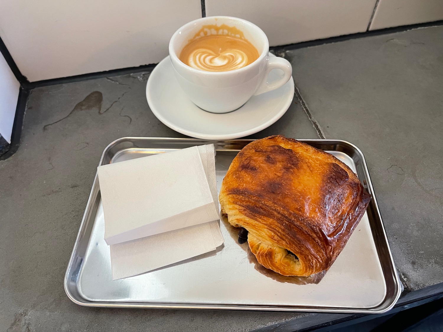 a tray with a pastry and a cup of coffee