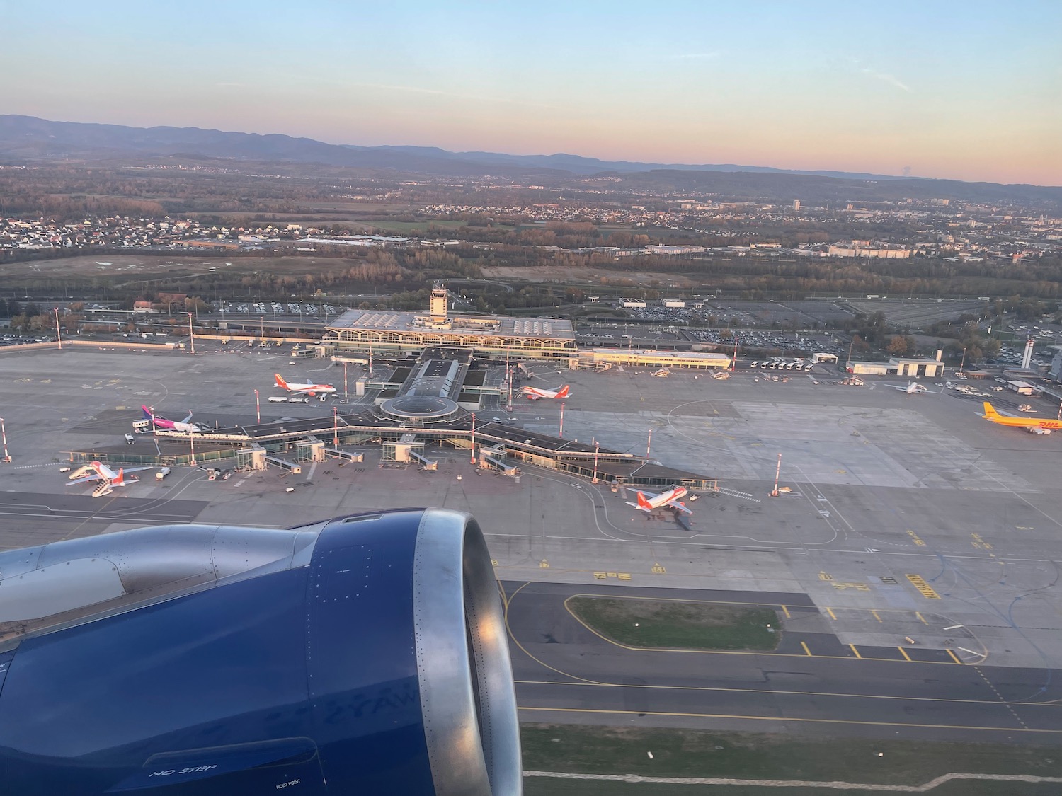 an airplane wing and a runway with planes in the background