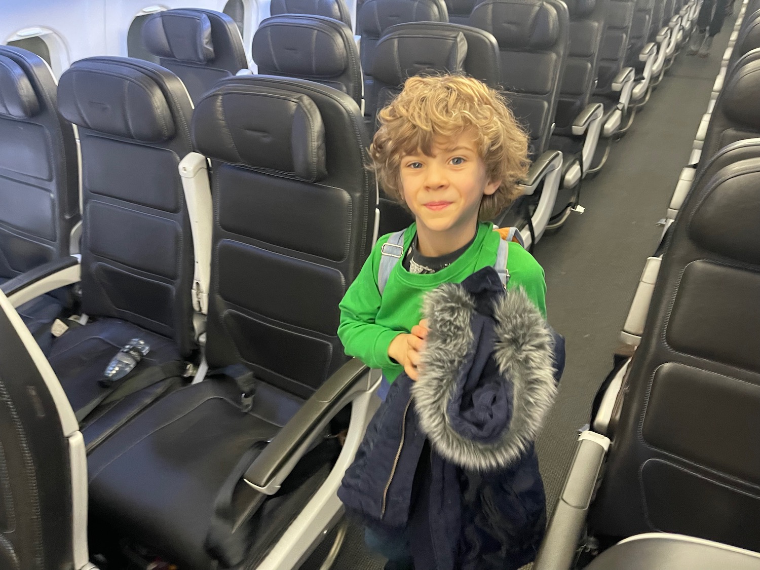 a boy standing in an airplane with a coat