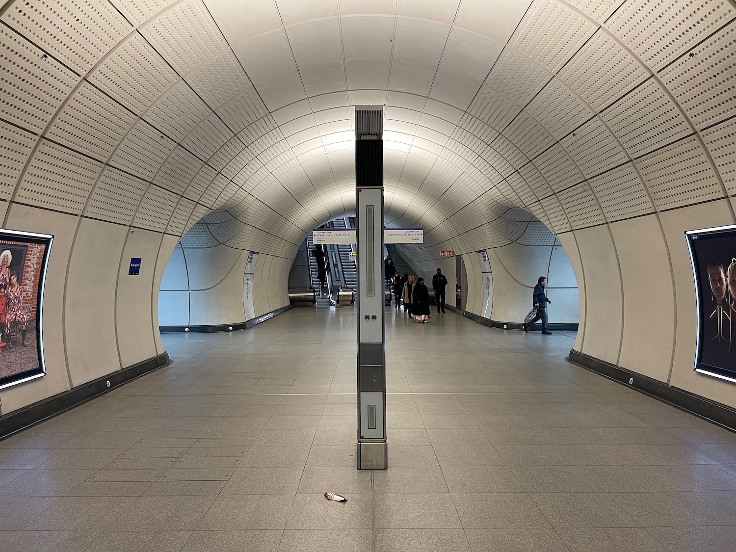 a white tunnel with a metal pole and people walking