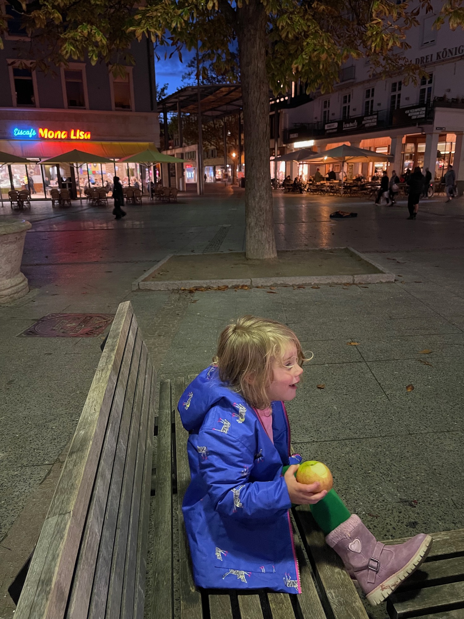 a girl sitting on a bench in a city