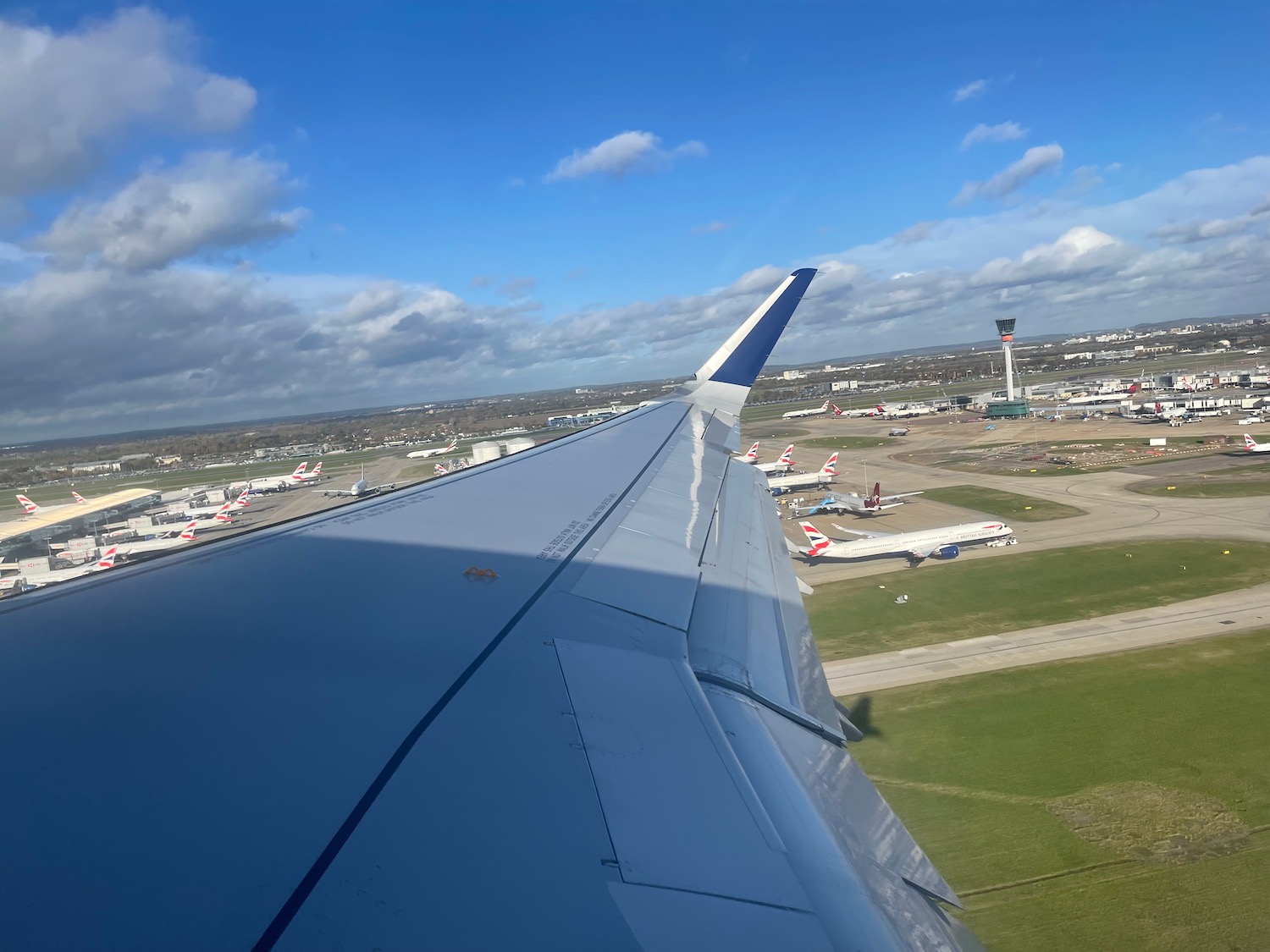 an airplane wing and runway with many airplanes in the background