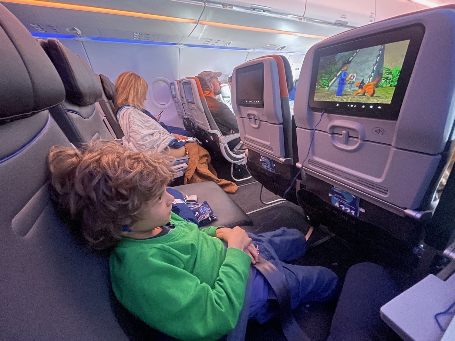 a child sitting in a seat with a television on the back of the seat