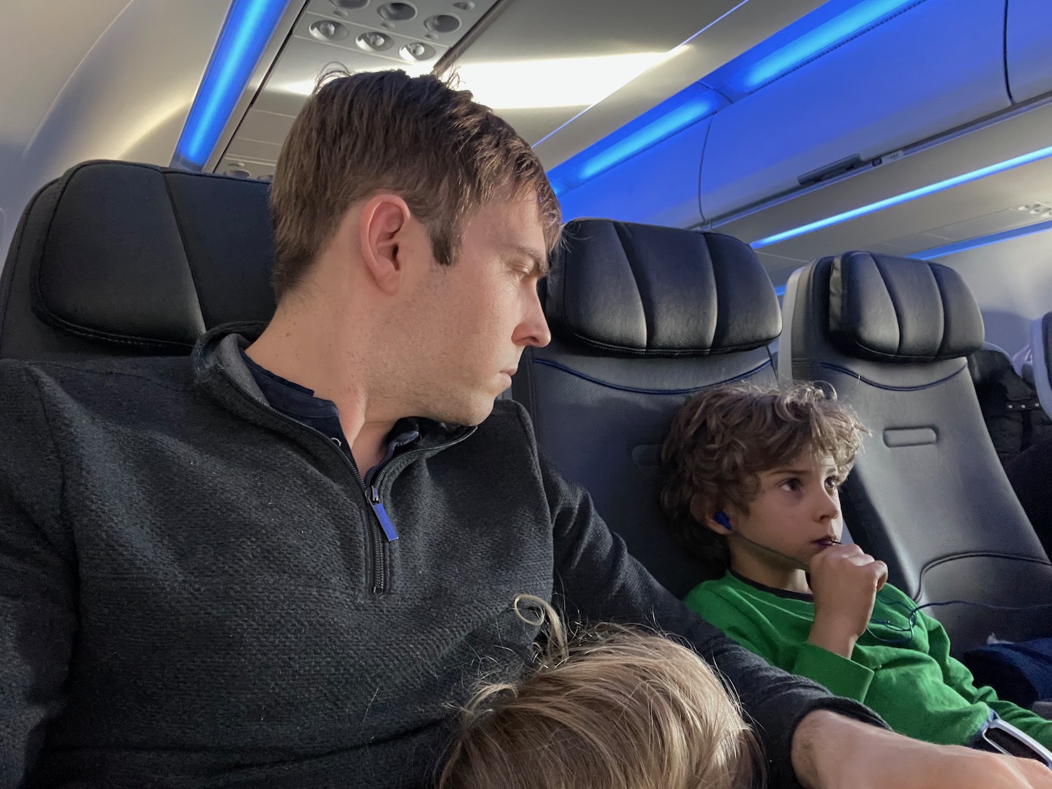 a man and two boys sitting in a plane