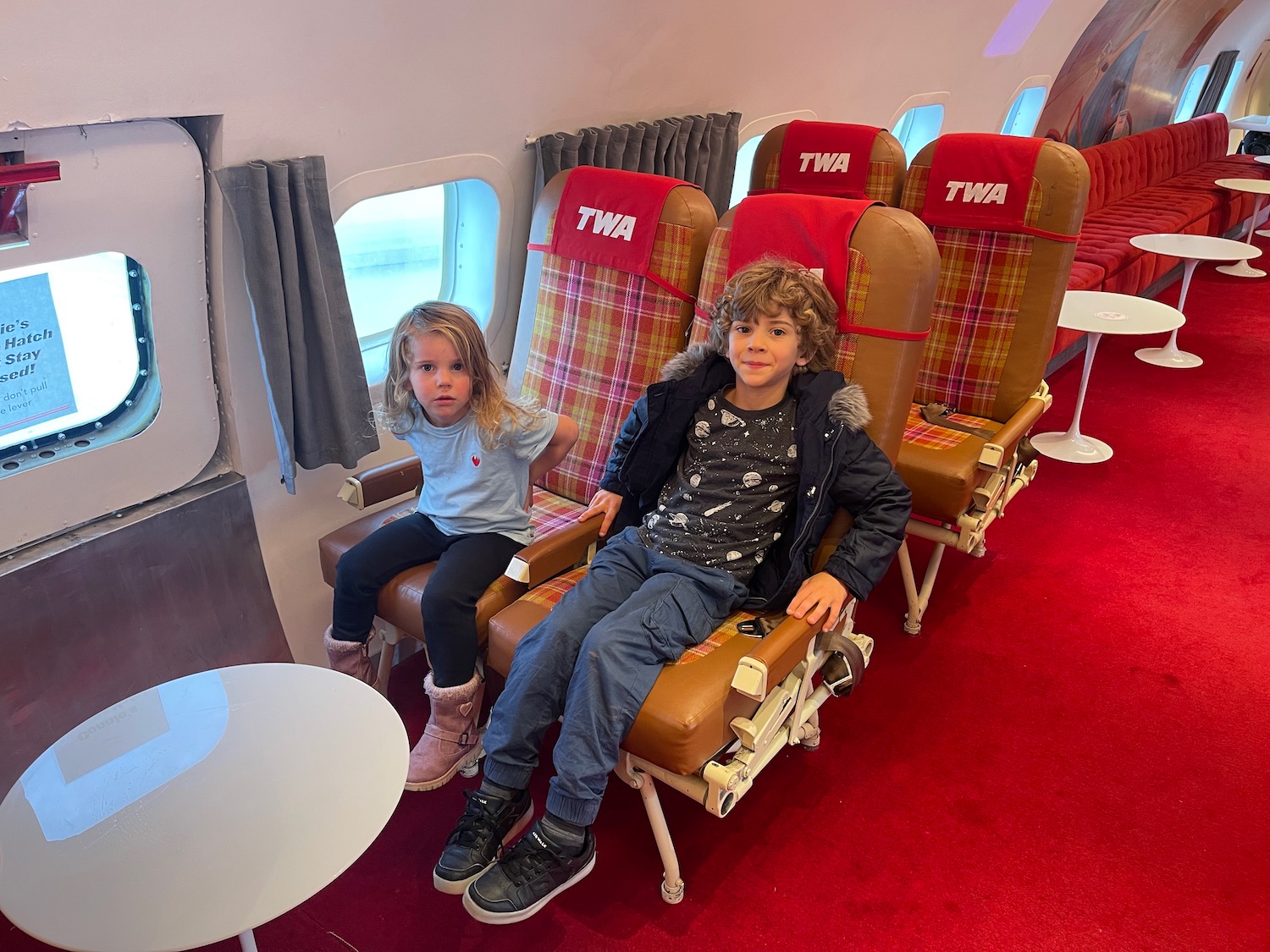 two children sitting in chairs on an airplane