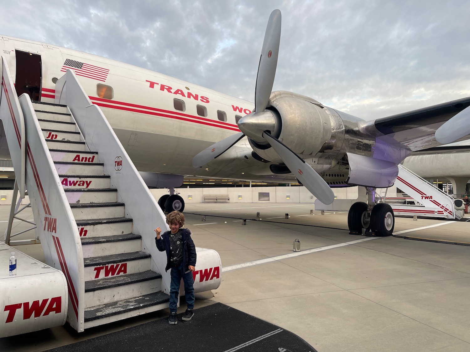 a boy standing on stairs next to a plane