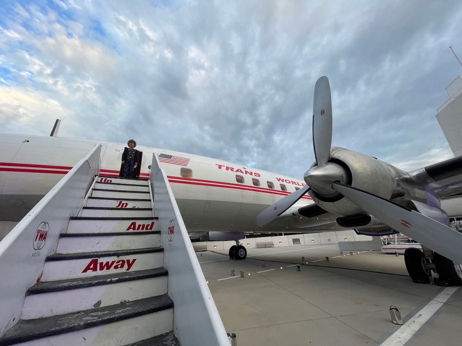 a person standing on stairs next to a plane