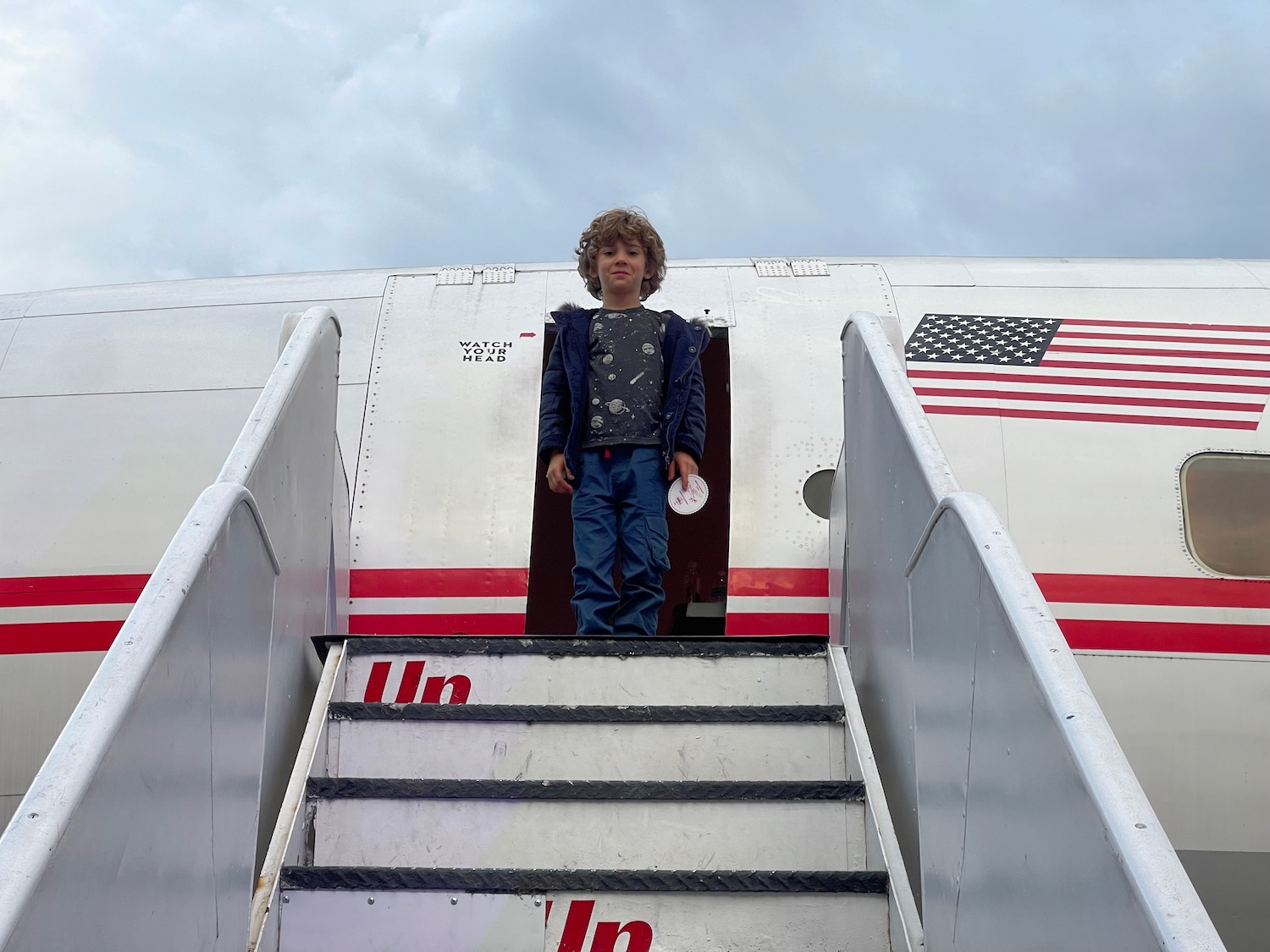 a boy standing on stairs of an airplane