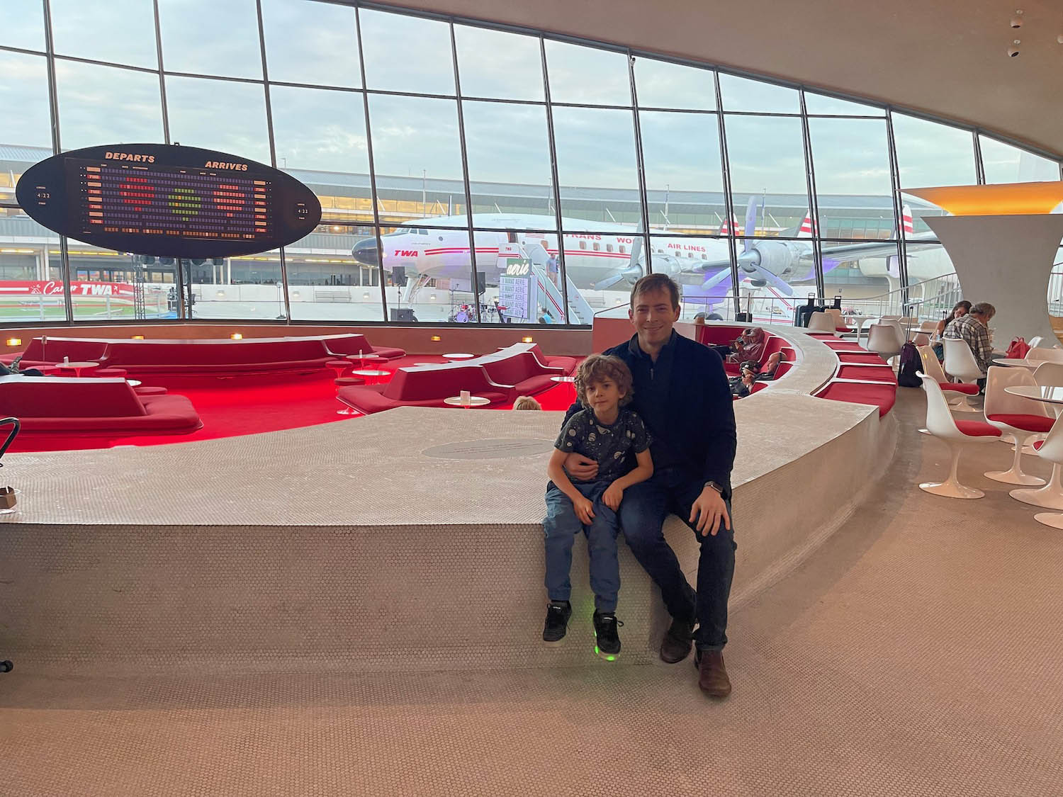 a man and child sitting on a wall in an airport