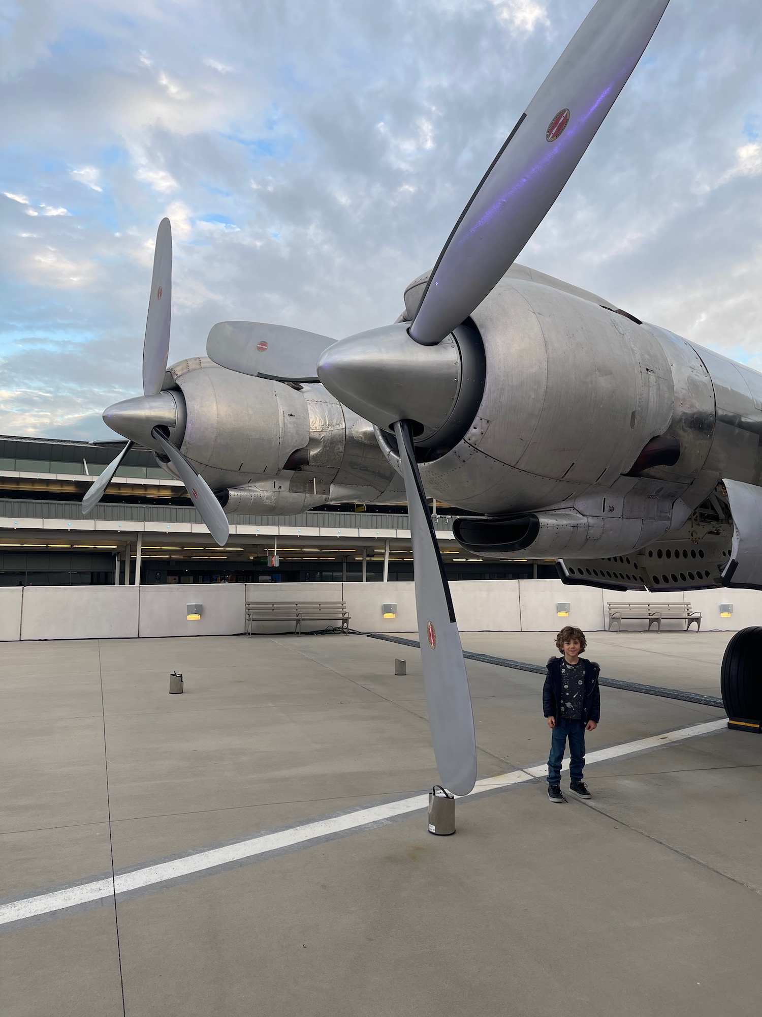 a boy standing in front of a large airplane