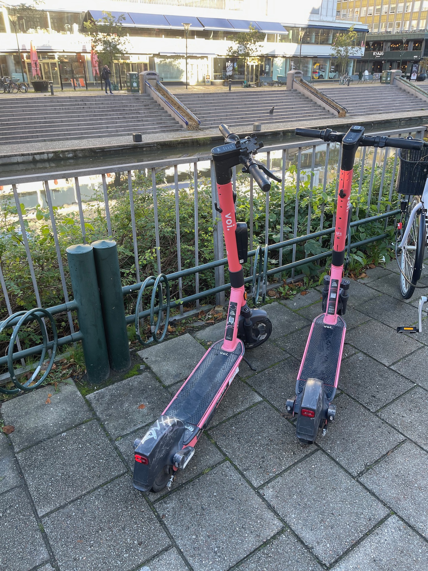 two pink and black scooters on a sidewalk