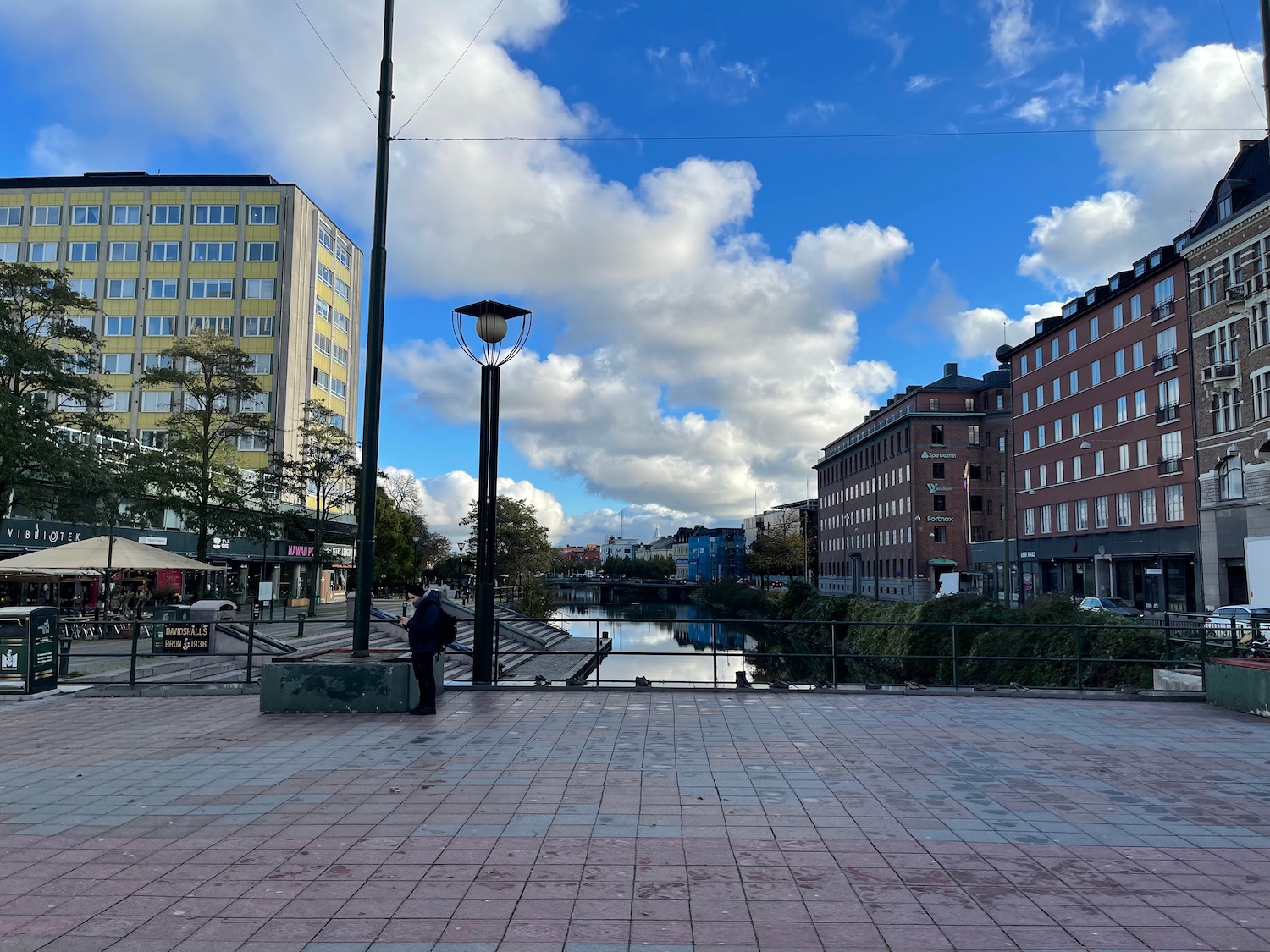 a person standing on a brick walkway next to a river