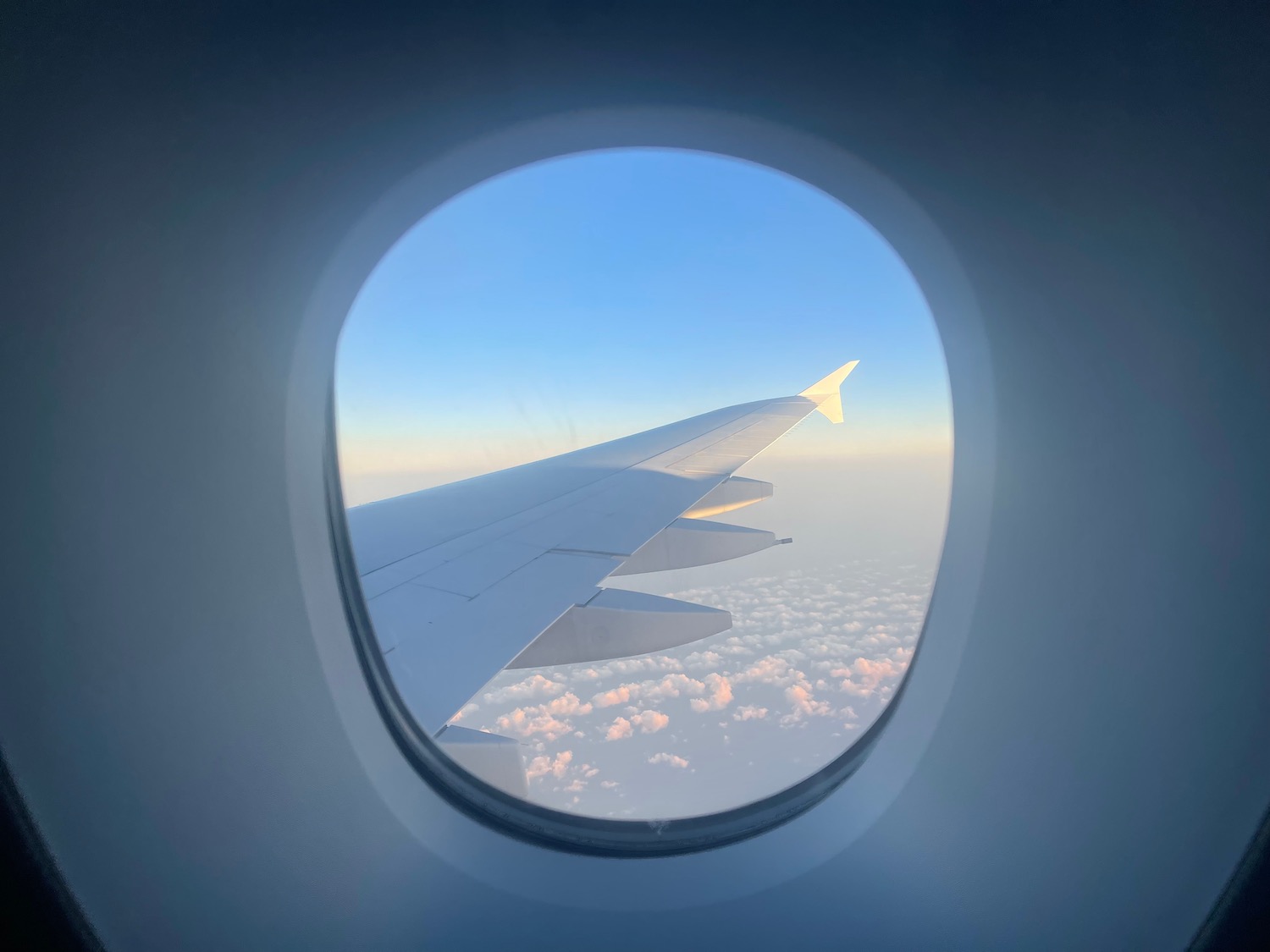 an airplane wing and sky seen through a window