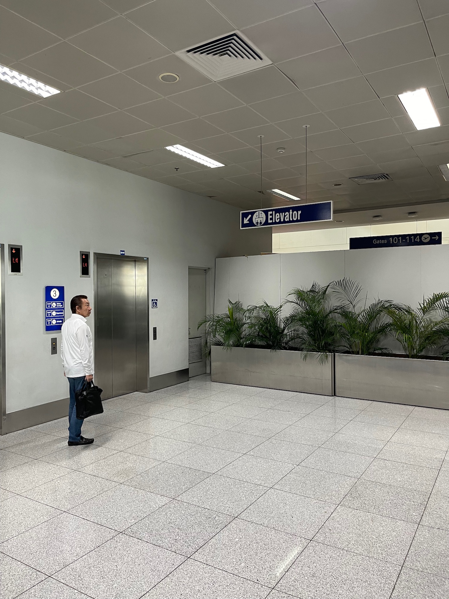 a man standing in a hallway with plants in front of them