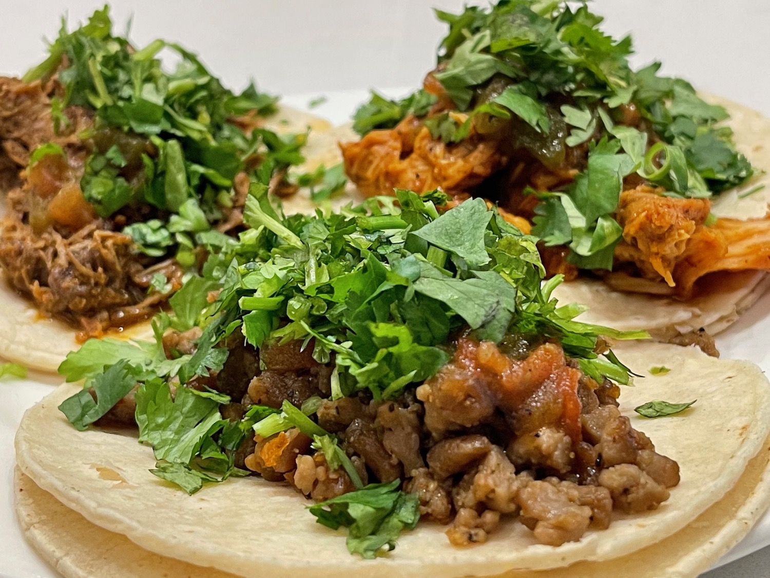a group of tacos with meat and greens