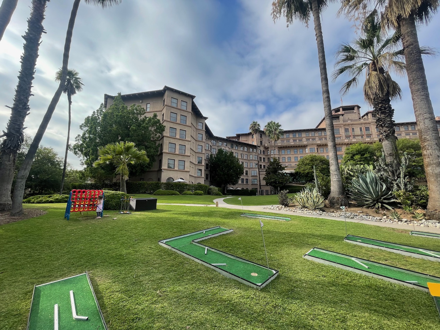 a group of golf course in a grassy area with trees and buildings